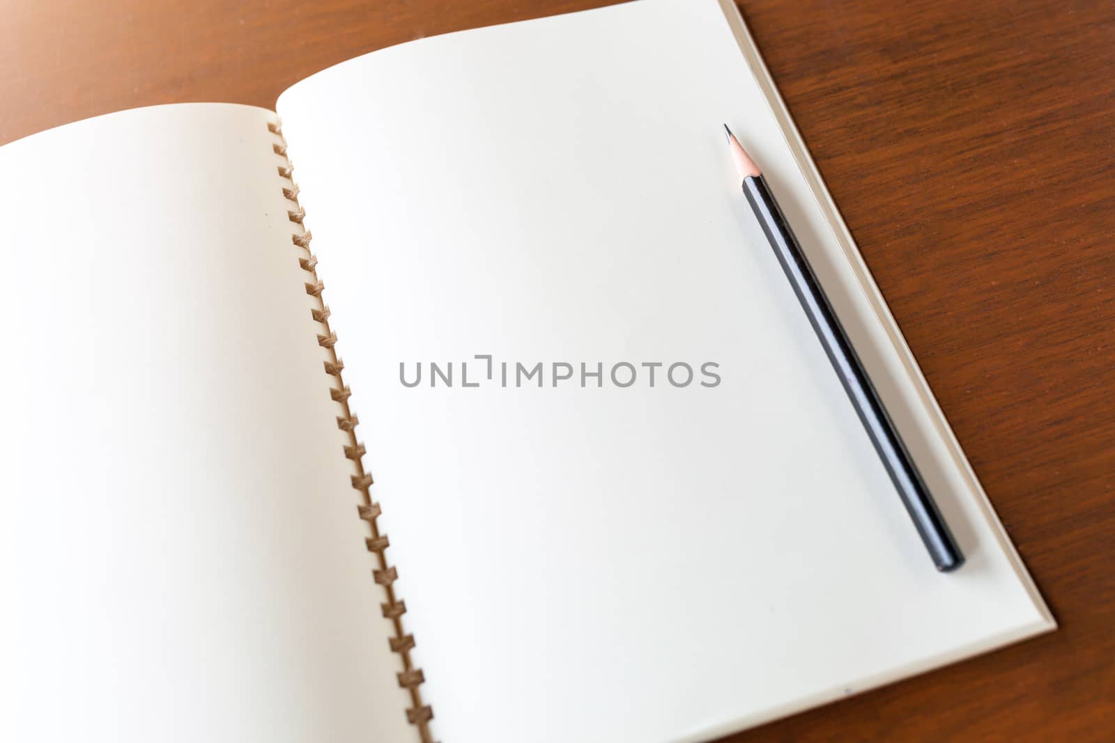 Blank note book with pencil on wooden table background concept a by nopparats