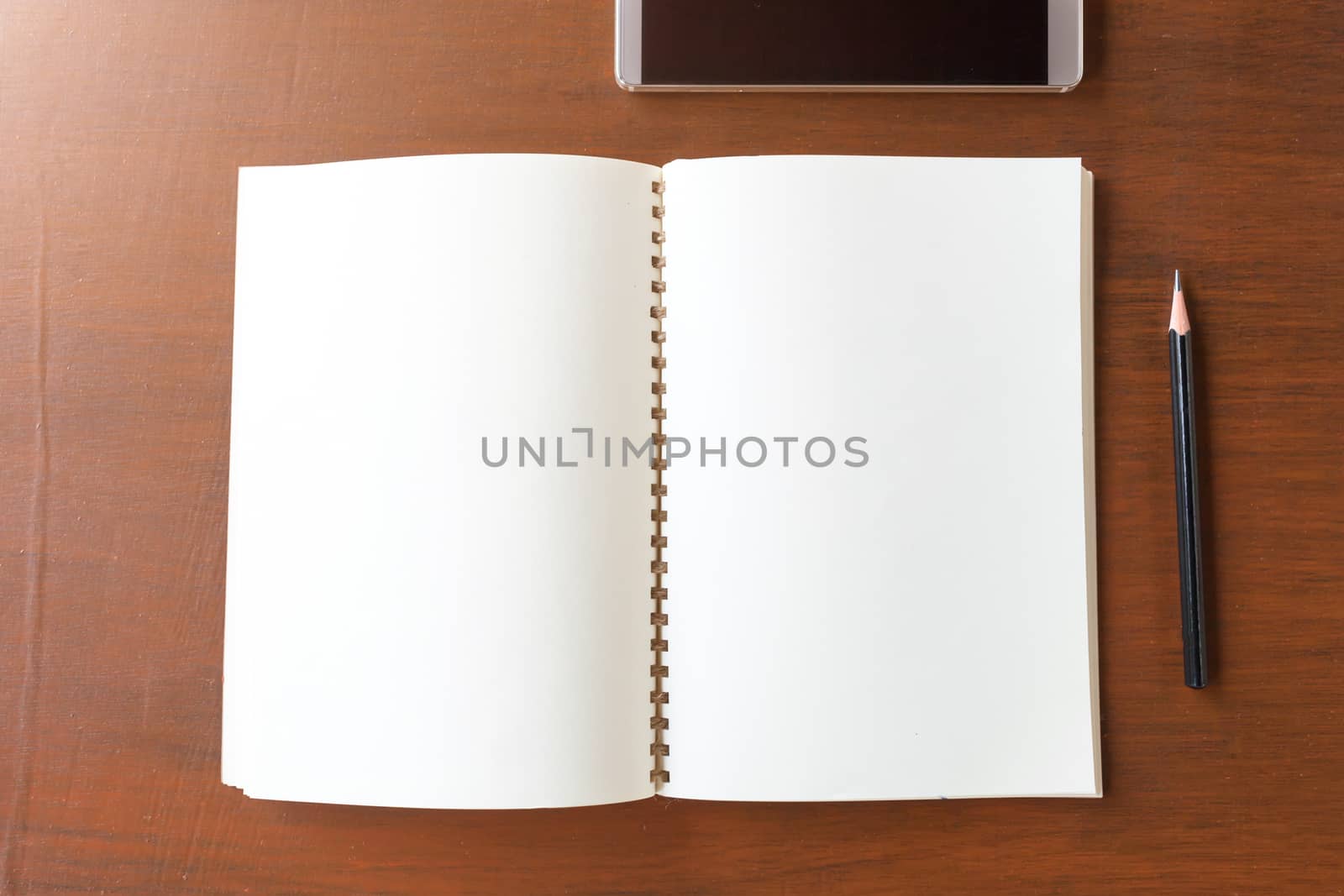 Blank note book with pencil and smartphone on wooden table background concept and Idea for write your text here.