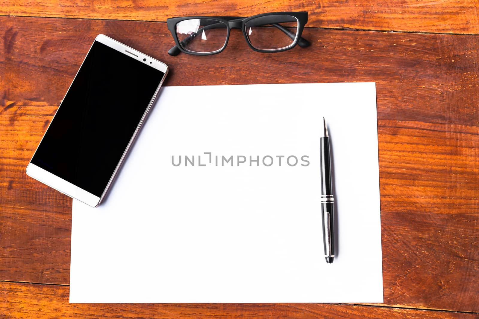 Blank paper with pen and smartphone on wood table concept and Idea for write your text here.