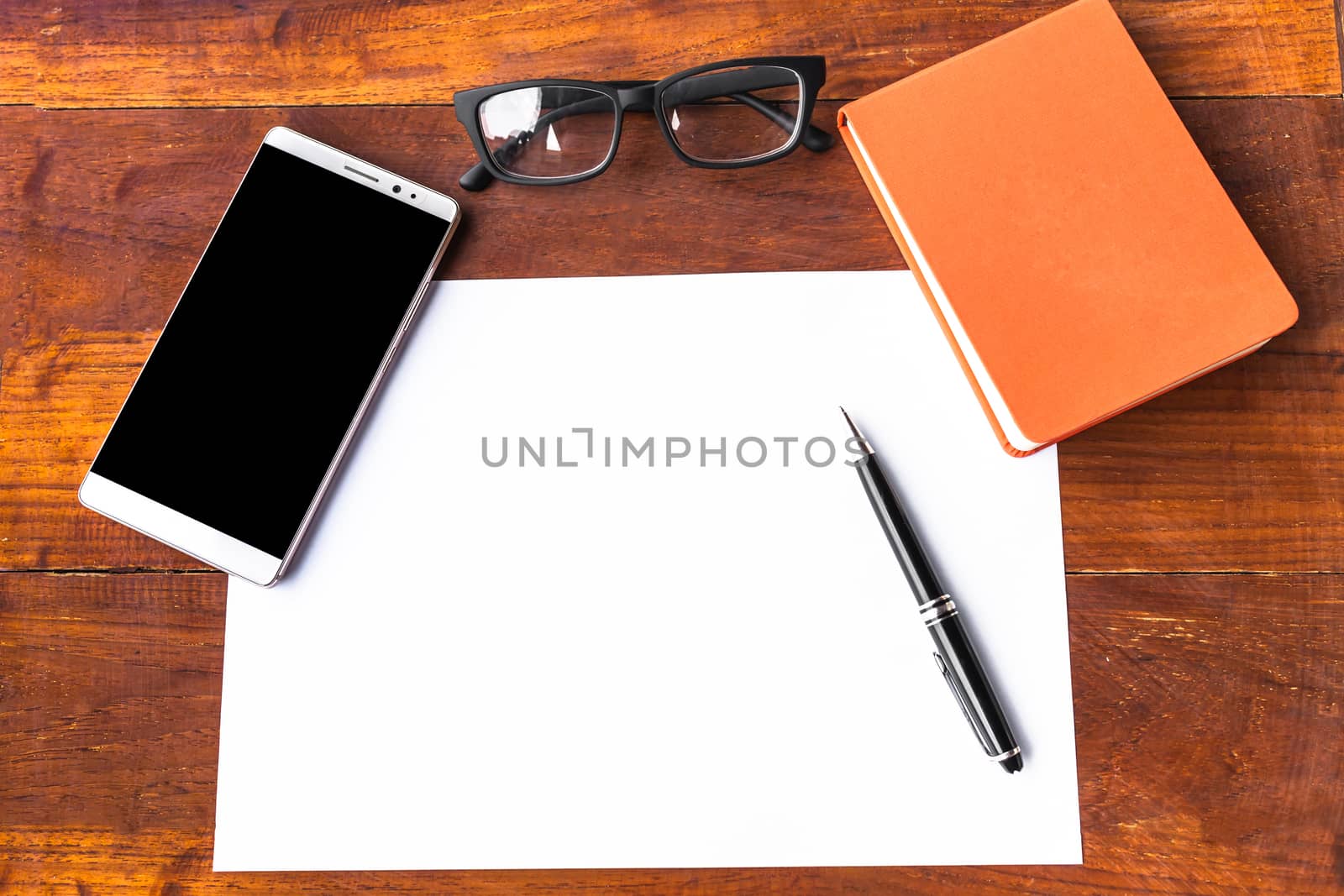 Blank paper with pen and smartphone on wood table concept and Idea for write your text here.