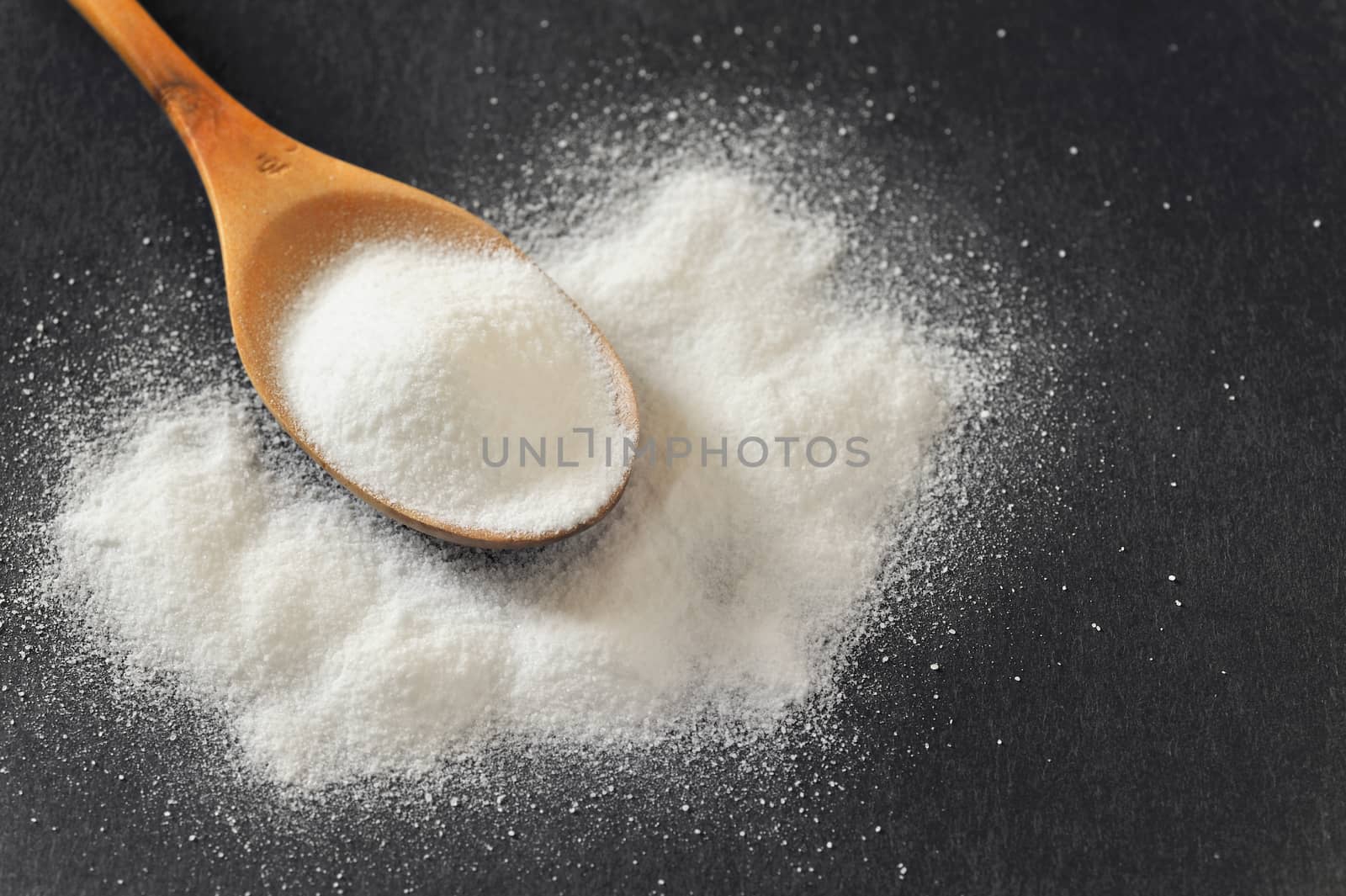 Bicarbonate in a wooden spoon on black background