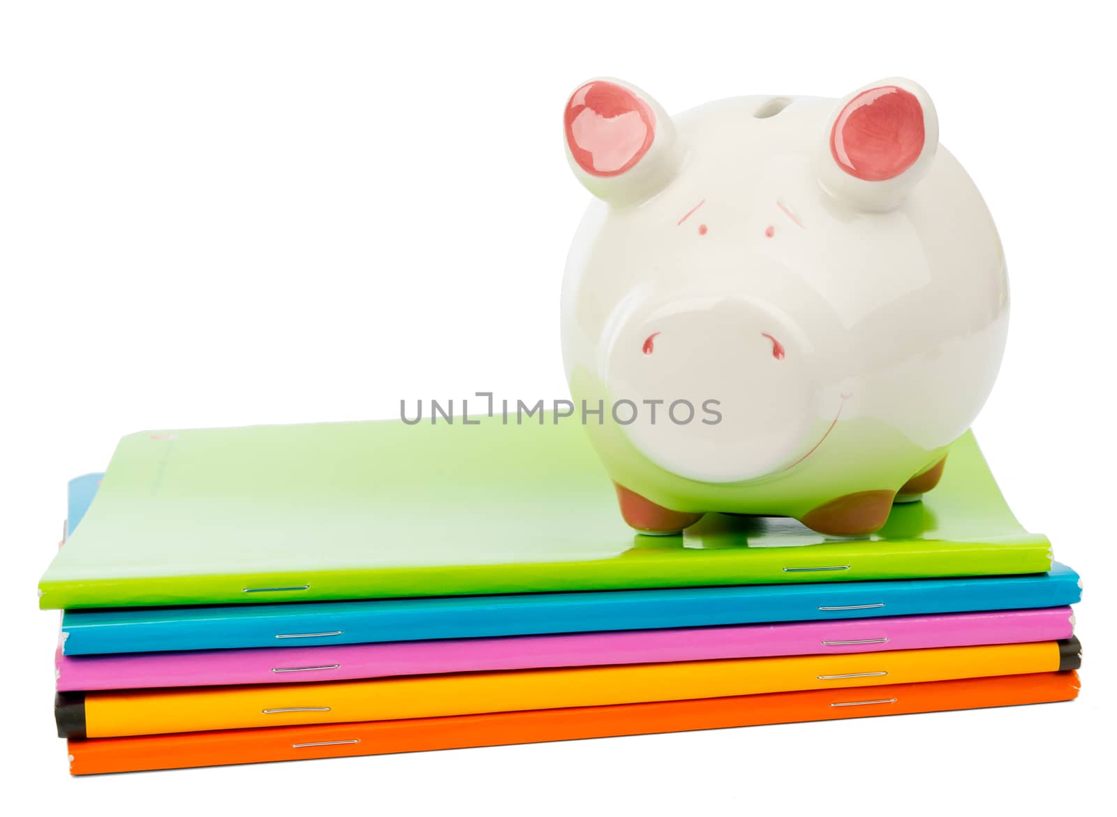 Piggy bank on pile of copybooks on isolated white background, front view