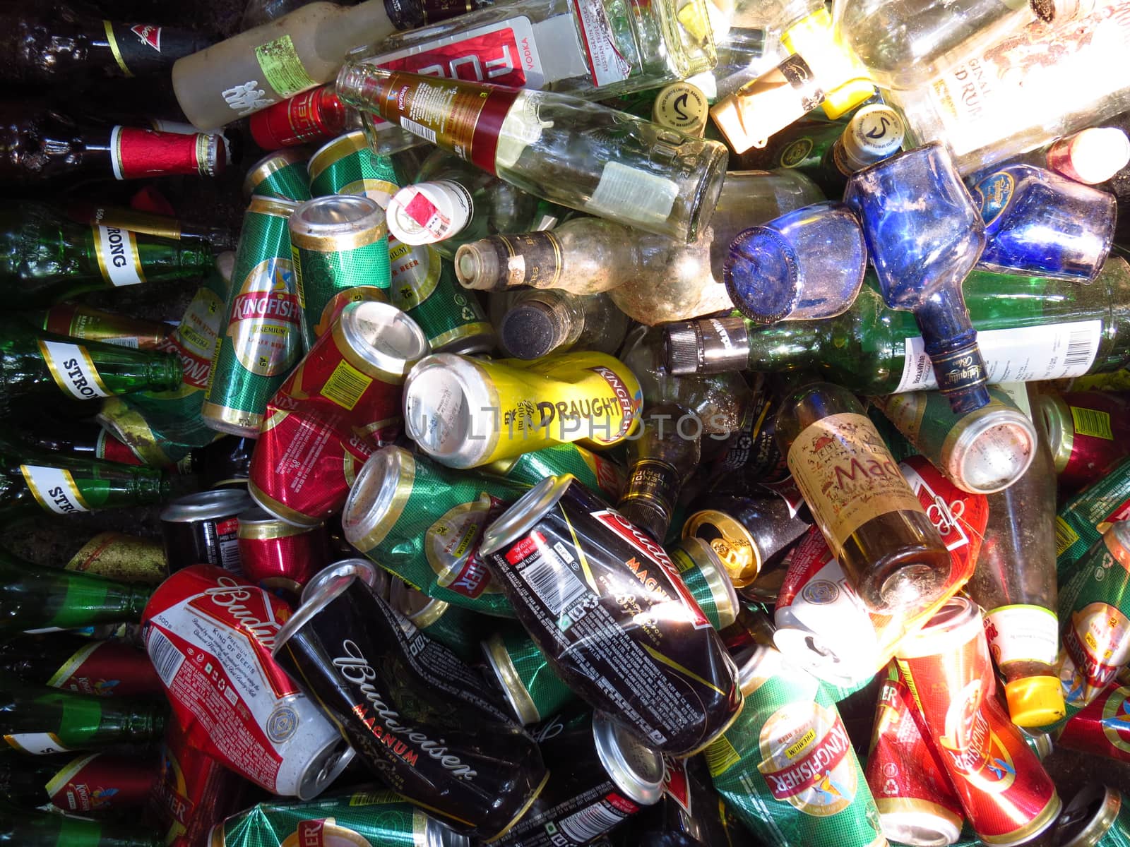 A background of thrash of alcohol bottles and cans lying in the outdoors.                               