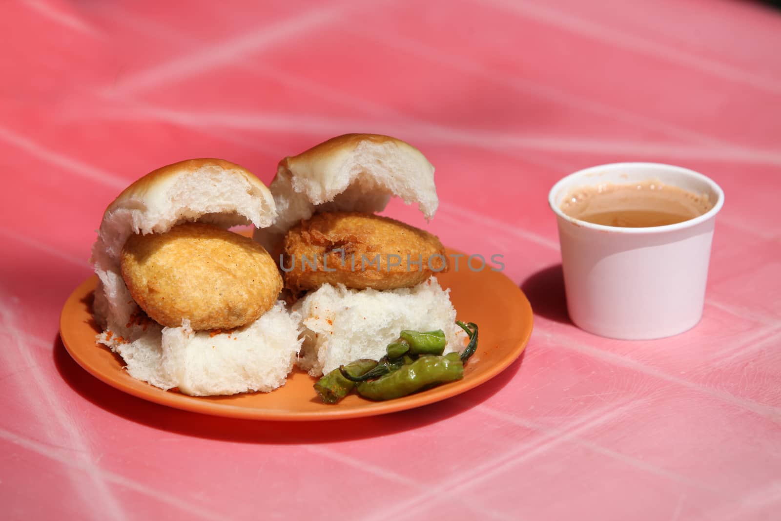 An Indian snack called Vada Pav which is like a potato burger or tikki n a bread, with a cup of tea