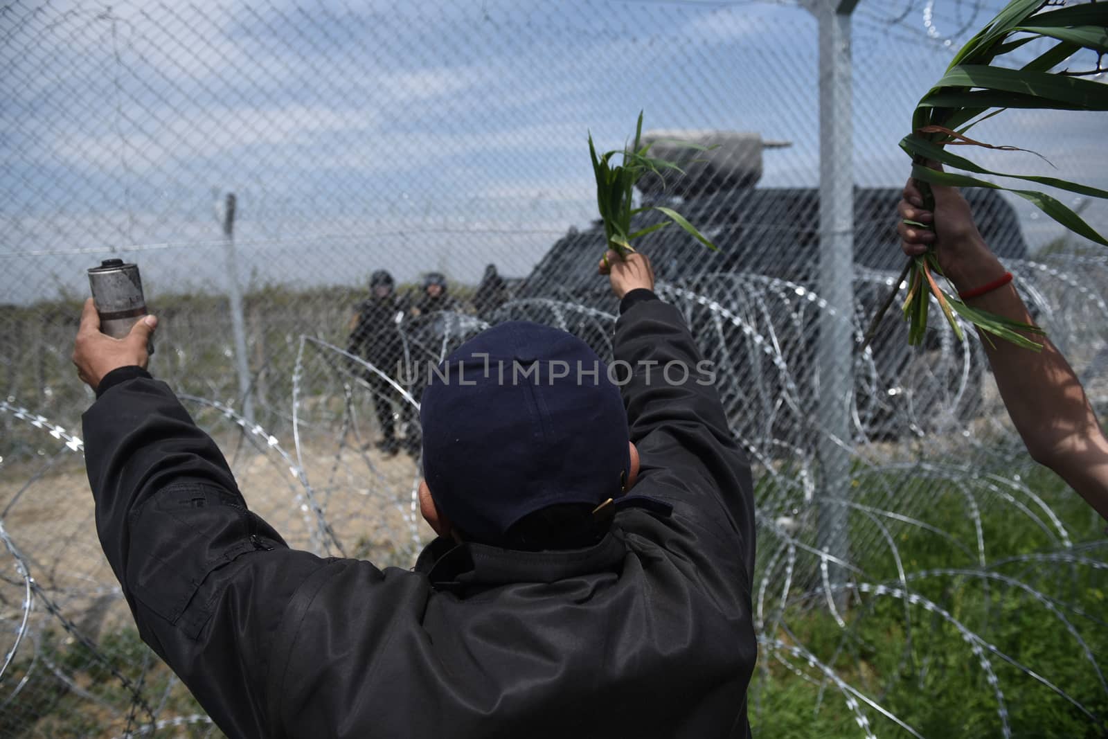 GREECE, Idomeni: A refugee holds up a used tear gas canister and leaves to Macedonian authorities near the Macedonia-Greek border on April 11, 2016 a day after clashes between the two groups.Hundreds of migrants were injured on Sunday as they attempted to cross the border into Macedonia. Police used tear gas, water cannons, and stun grenades to disperse the crowd as migrants threw stones in retaliation. 