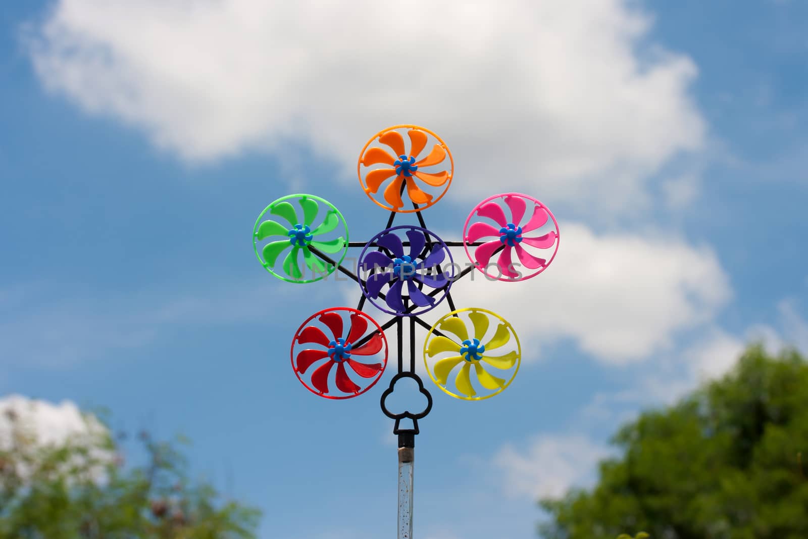 Colorful pinwheel against blue sky with clouds
