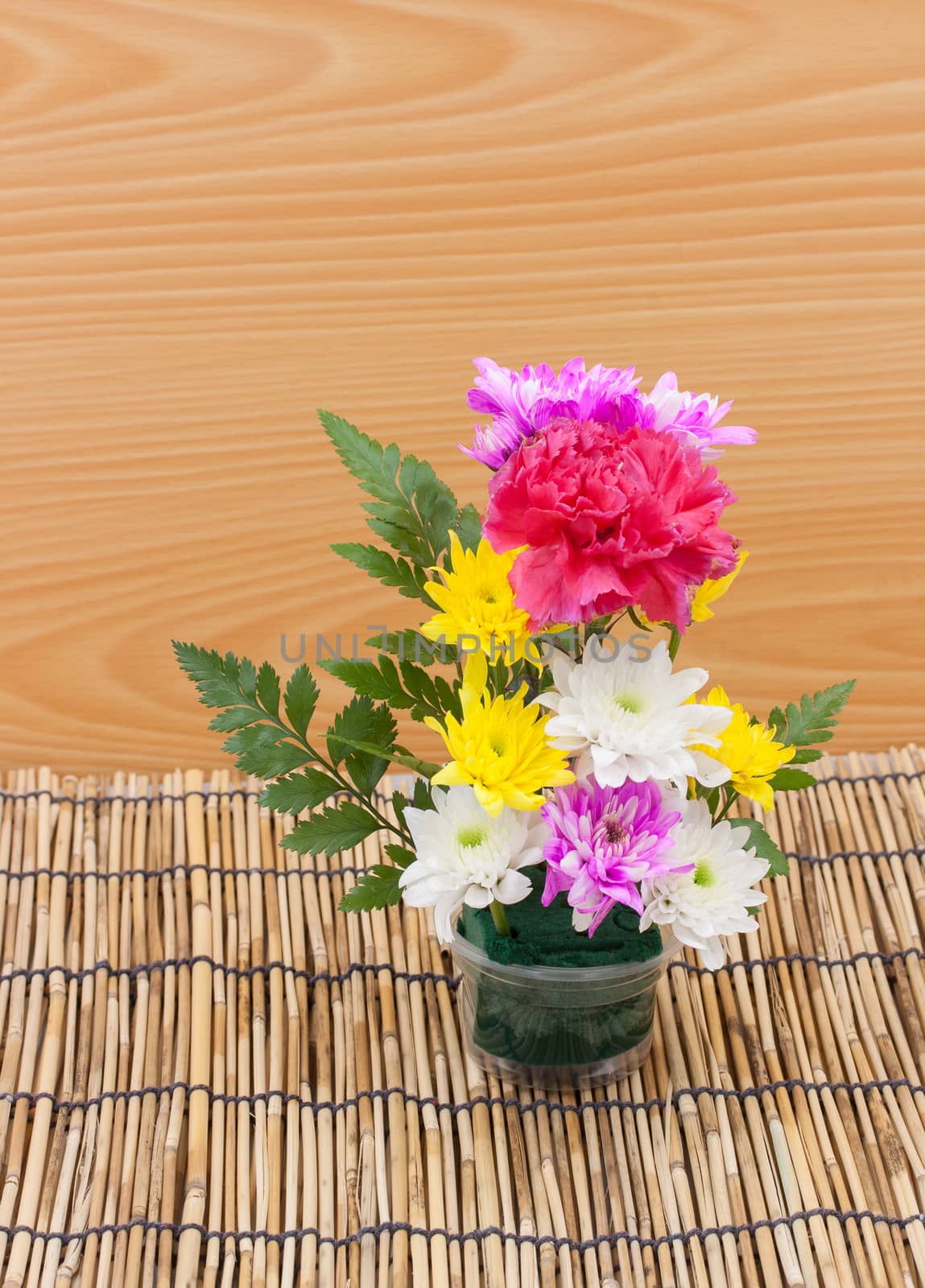 Colorful flower bouquet arrangement in vase on wood background