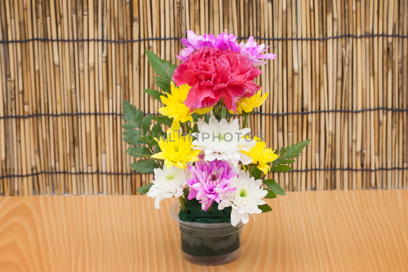 Colorful flower bouquet arrangement in vase on wood background