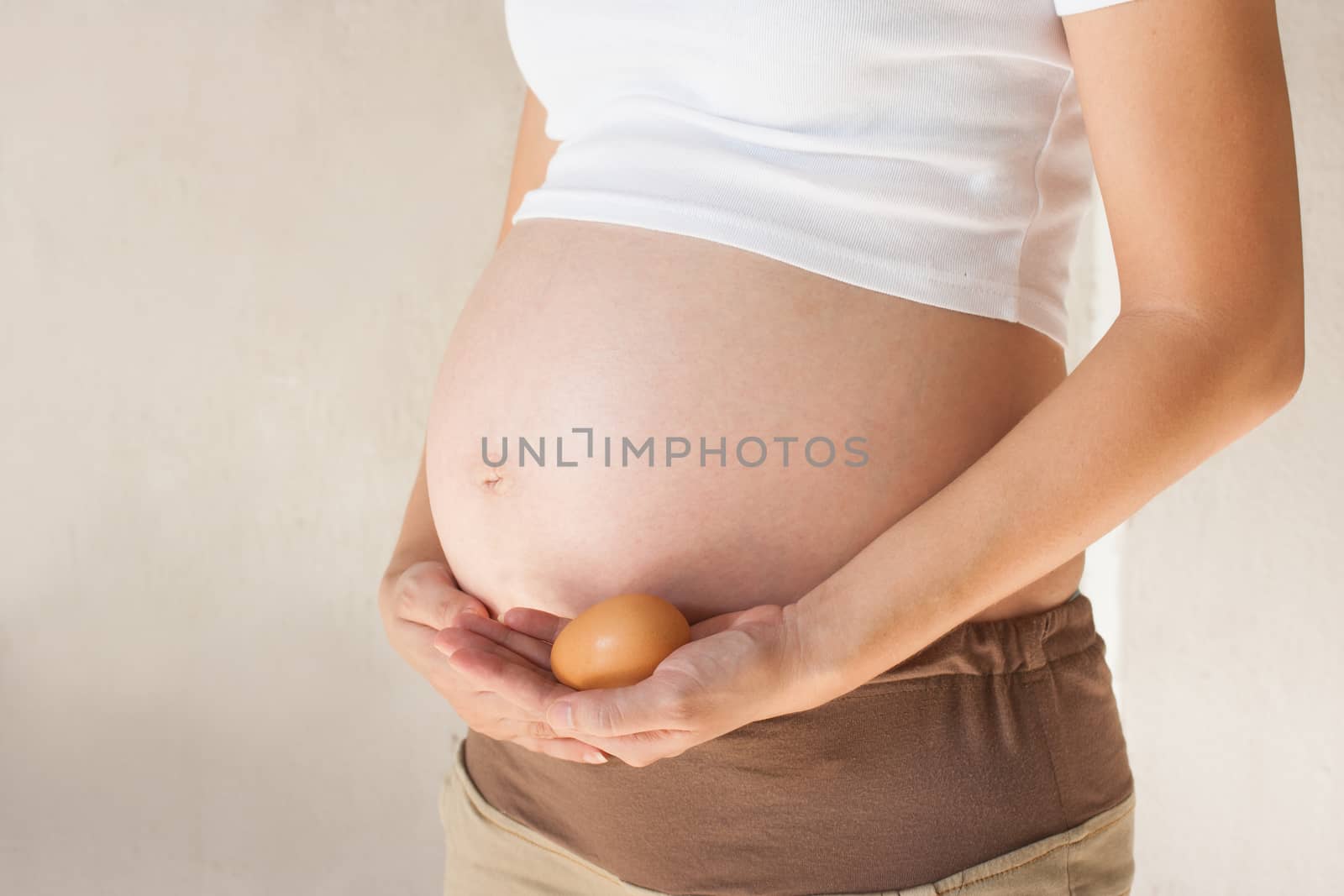 Pregnant woman's belly and egg in hand by pkproject