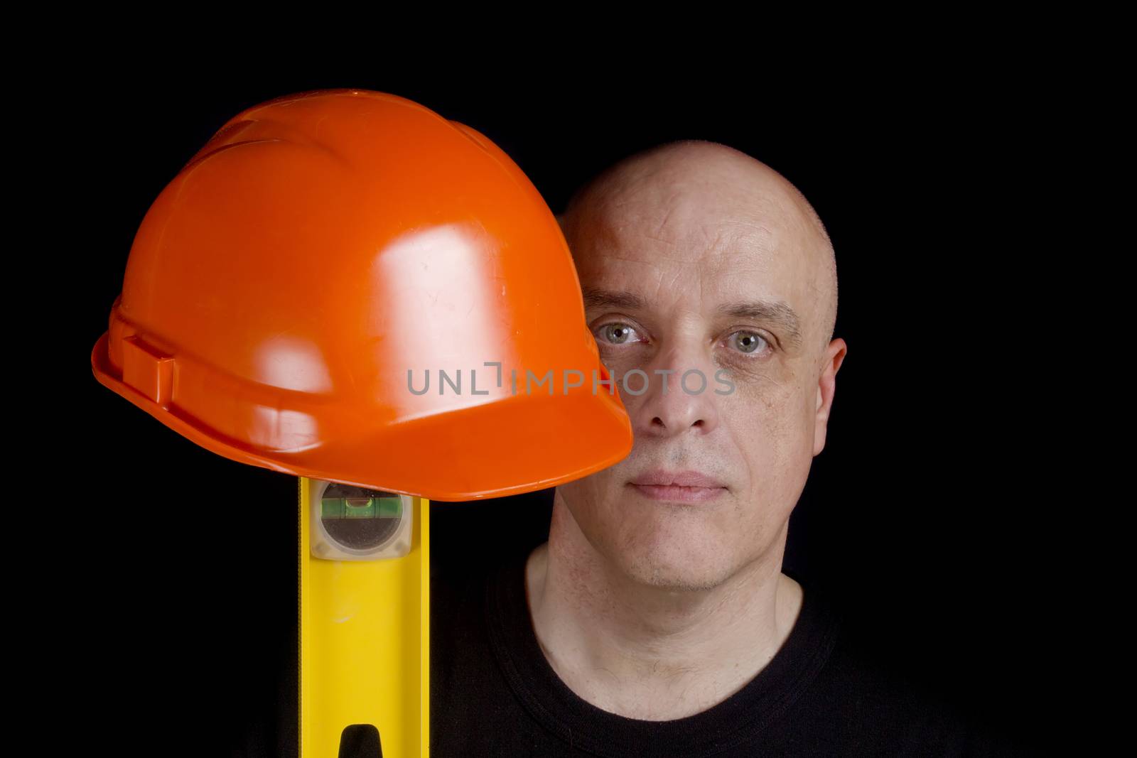 Construction worker with protection helmet and level on a black background