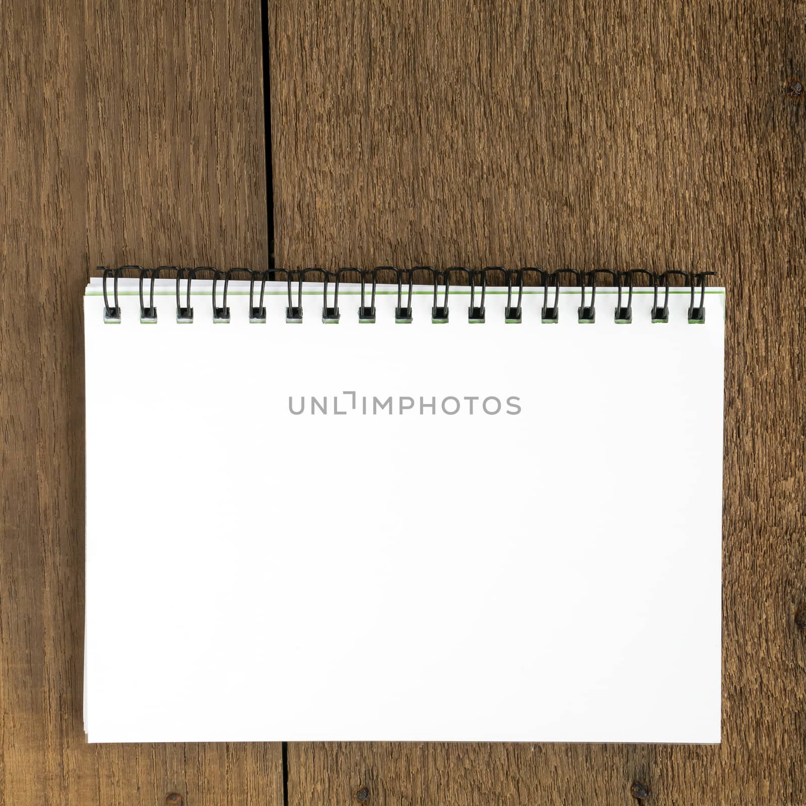 The close up of blank white notebook on wooden plank background.