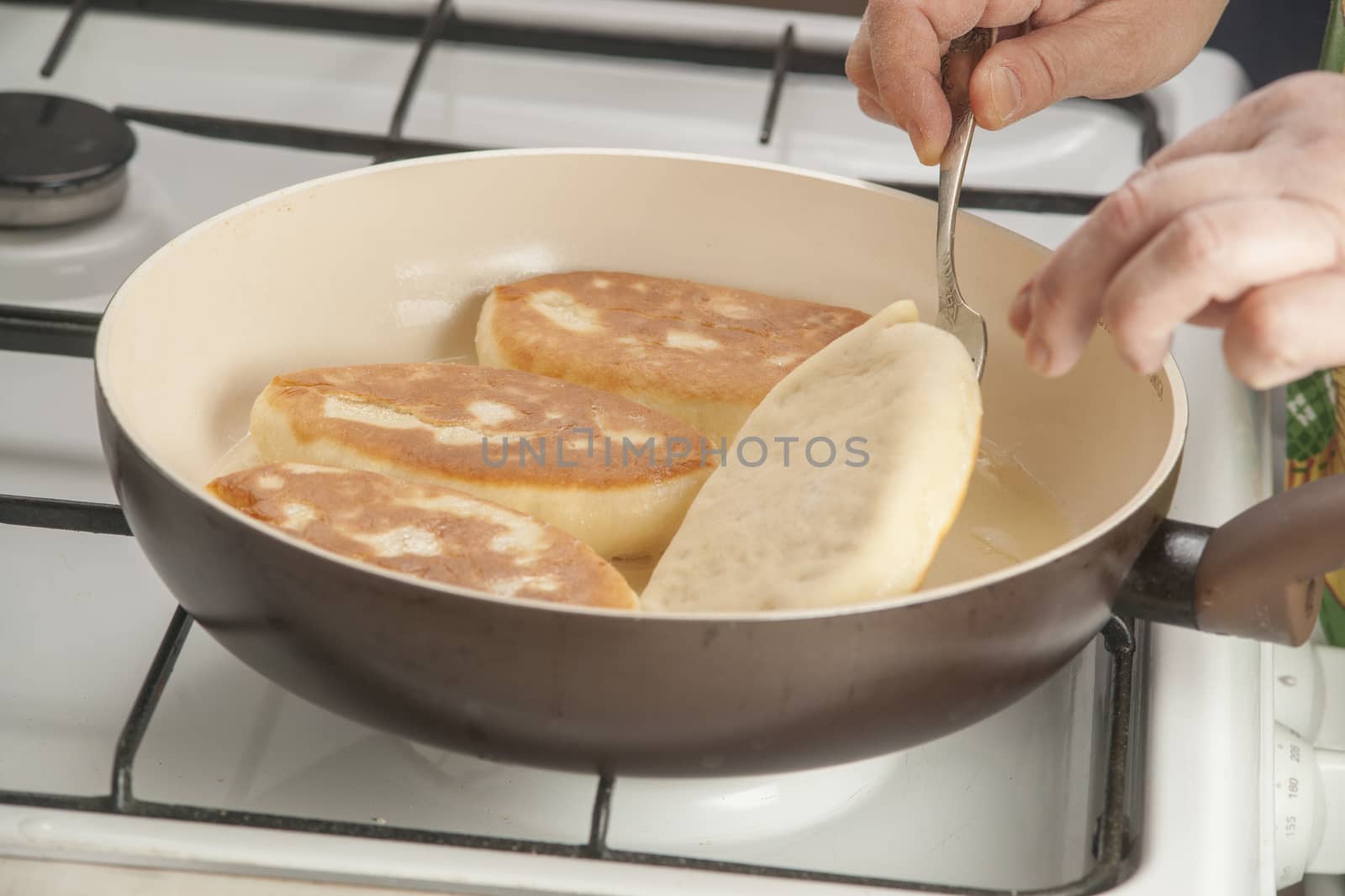 Patties with potato in the pan on the stove burning flame.