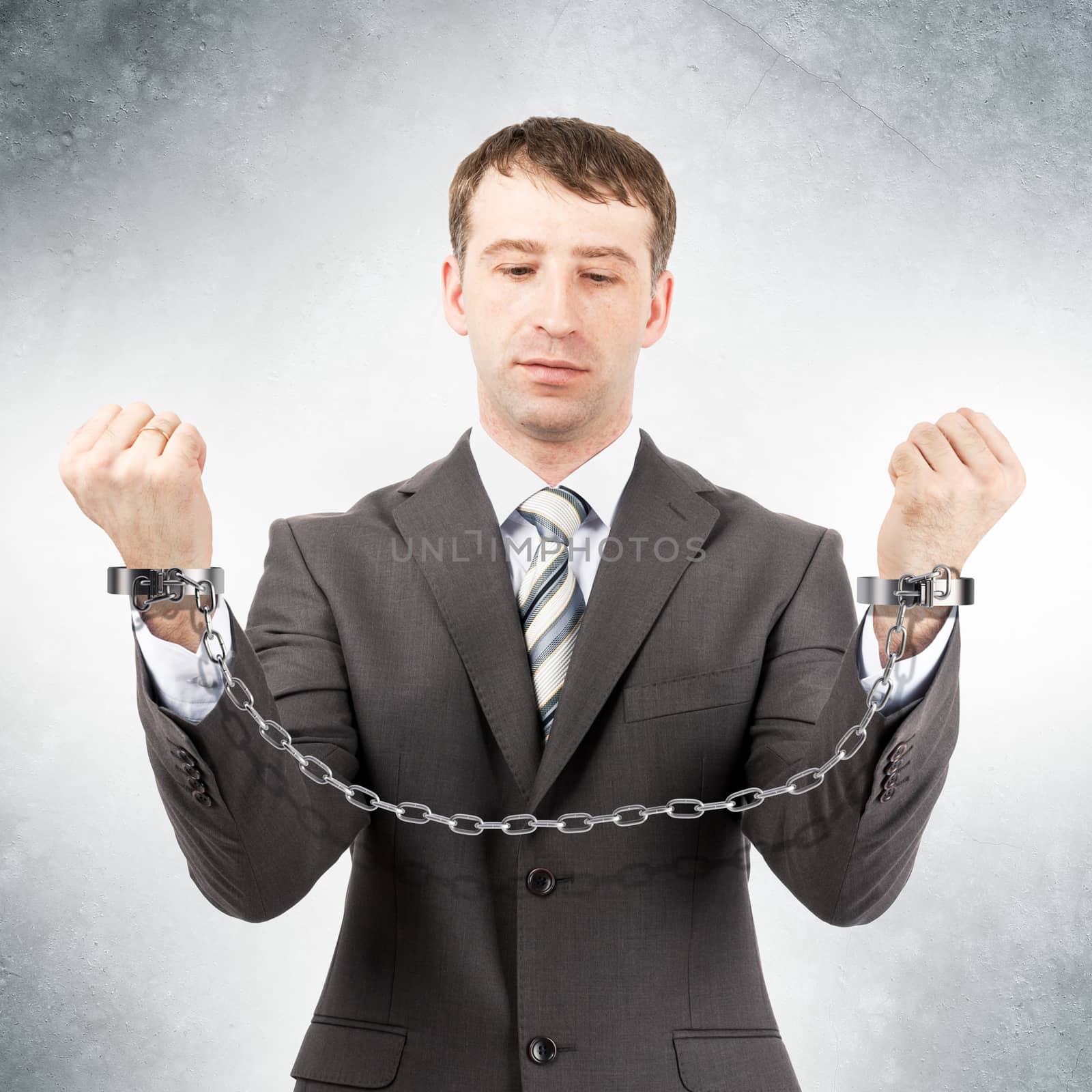 Businessman looking at cuffs on grey wall background
