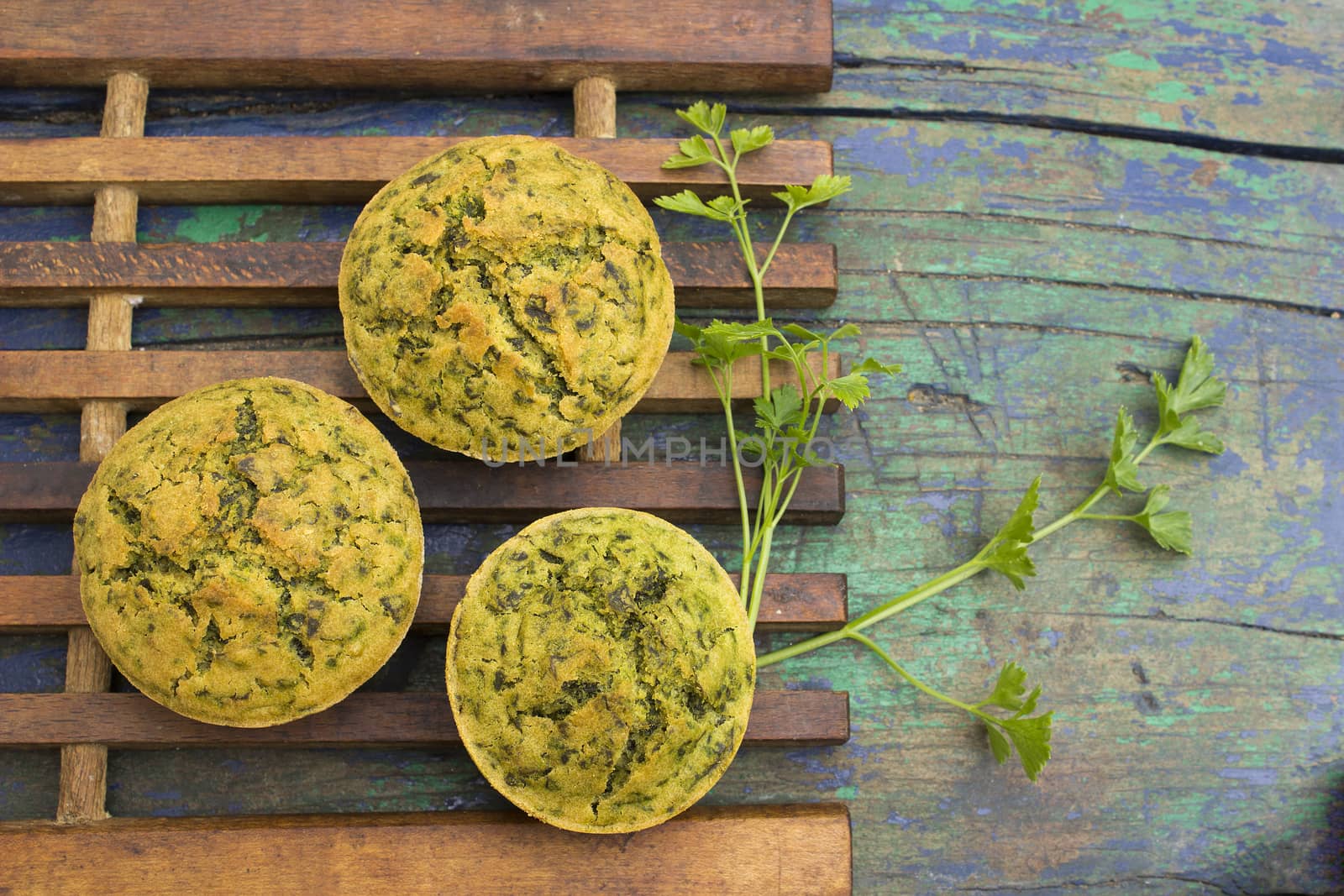 Freshly baked muffins with spinach on a wooden background