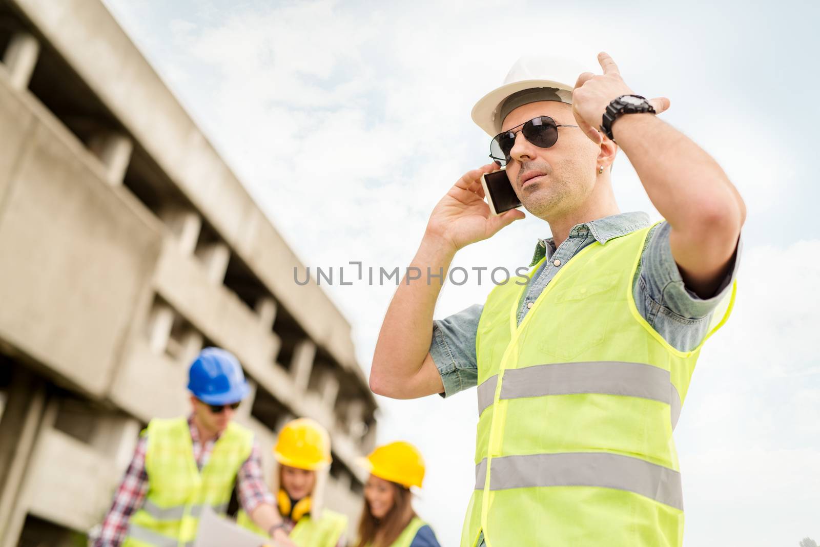 Construction architects using phone in front building damaged in the disaster.