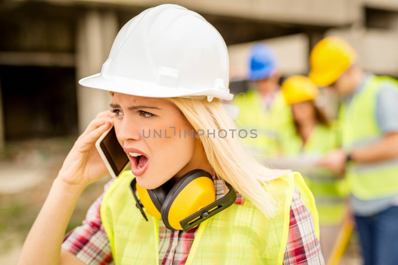 Beautiful young female construction architects using phone at a construction site.
