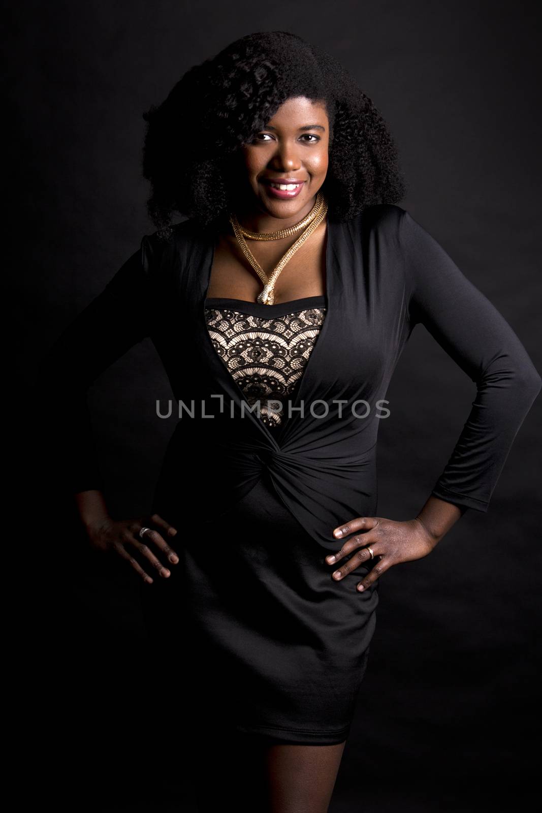 beautiful young black woman is wearing dark dress on grey background