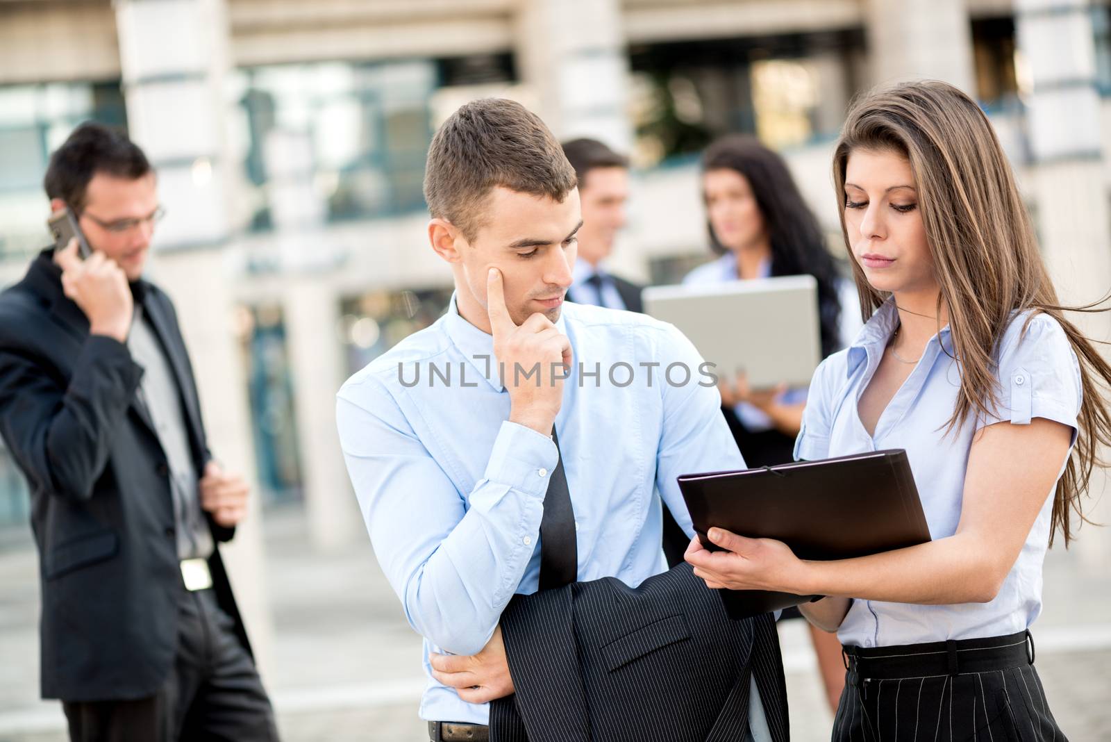 Young businessman talking to his pretty woman business partner in front of office building.