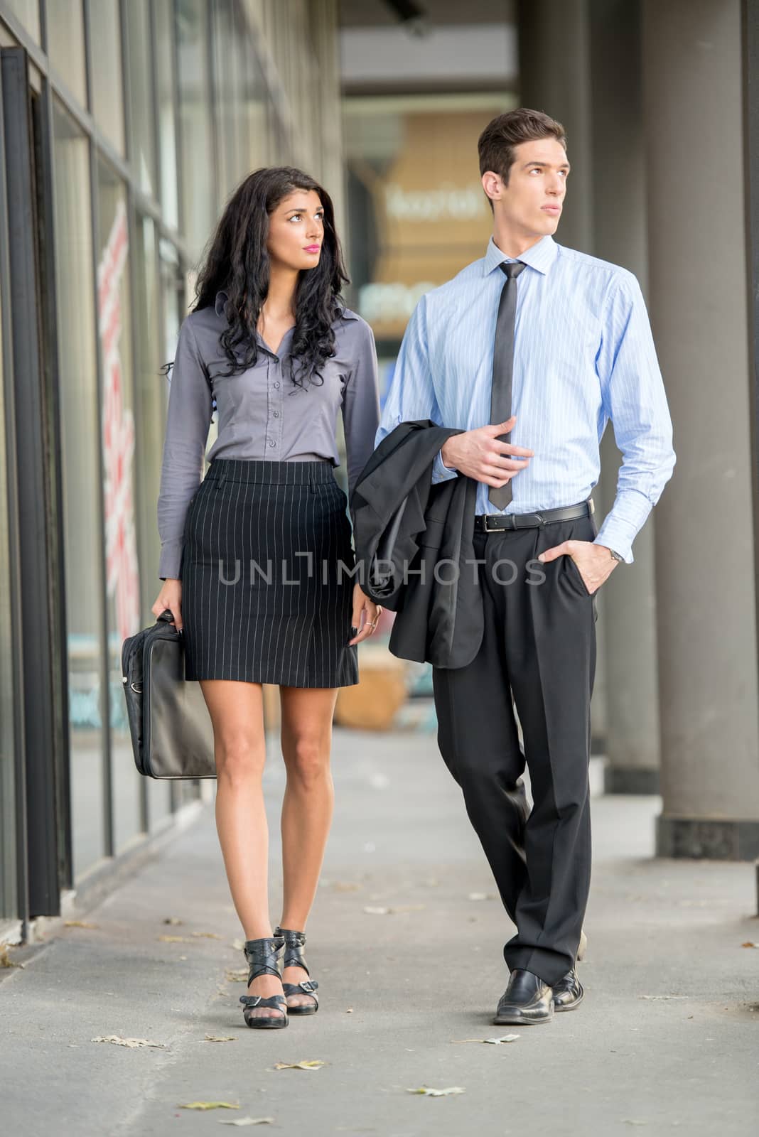 Handsome pair of young businessmen and businesswomen walking outside. 