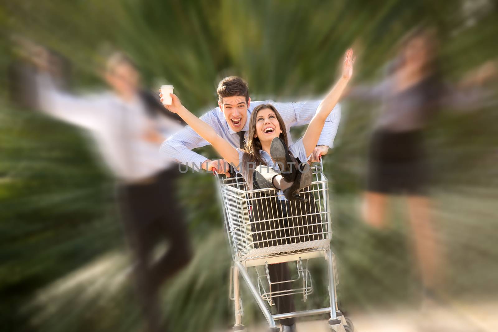 Young business people, elegantly dressed, in a park with a shopping trolley, which pushed their colleague, in euphoric motion.