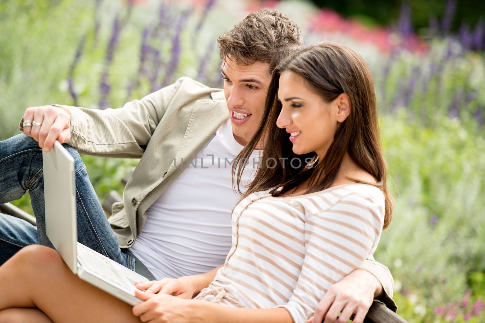 Young Couple Using Laptop At Park  by MilanMarkovic78