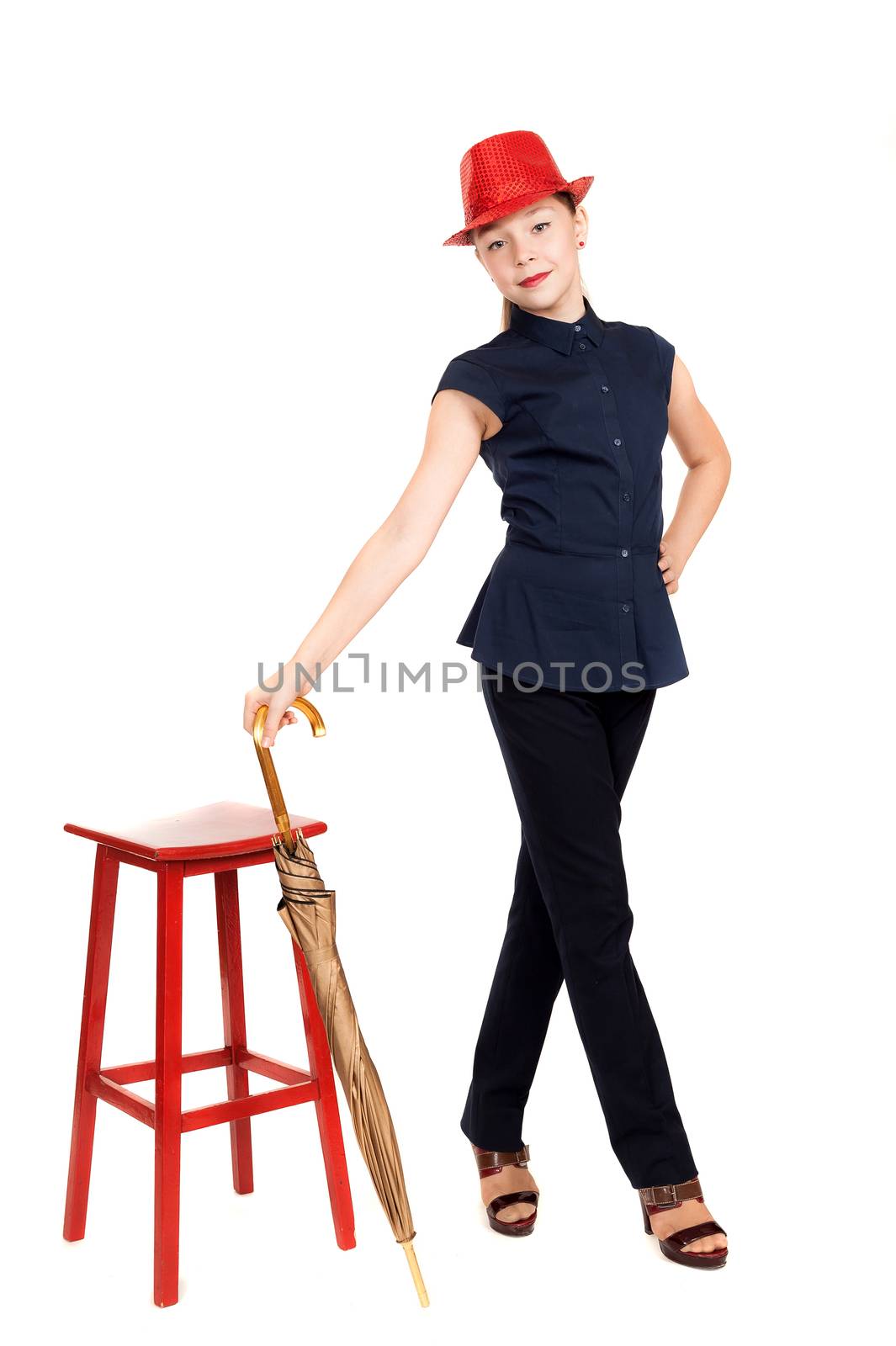 The girl the teenager in a suit and a hat with an umbrella in hands about a red chair on a white background