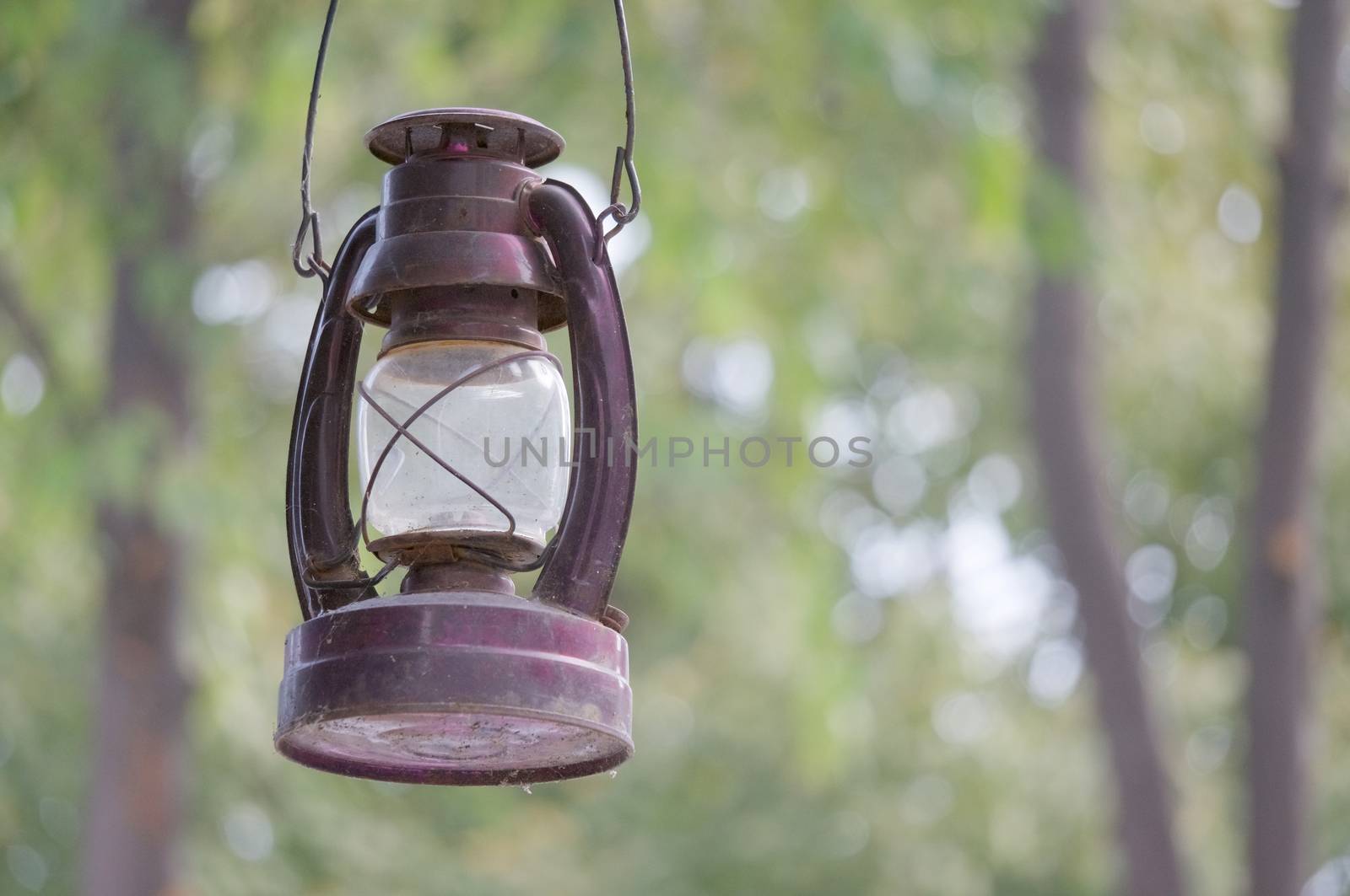 Old and rusty kerosene lantern hanging at cabin have bokeh as background.