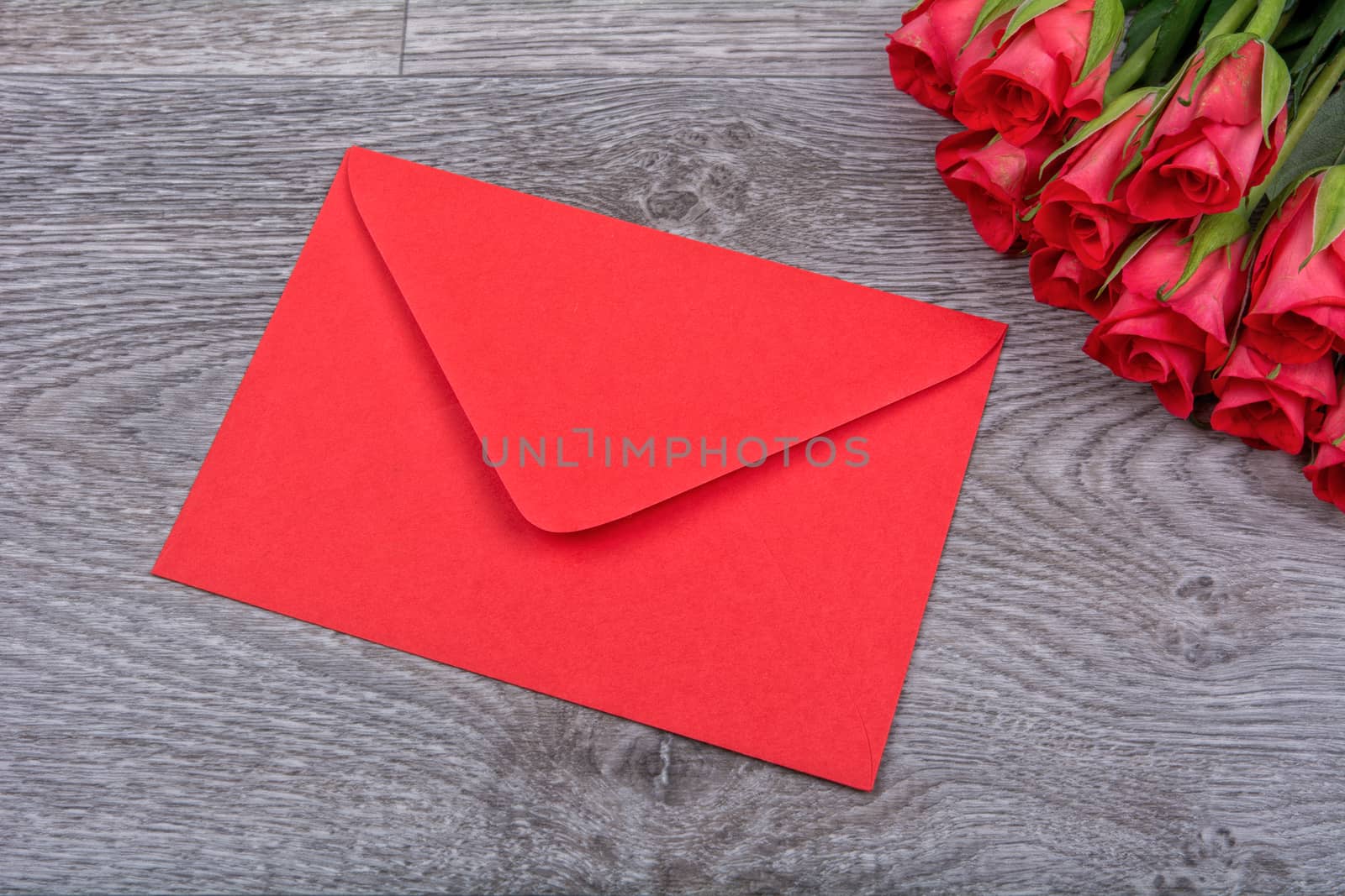Red envelope and red roses on a wooden background