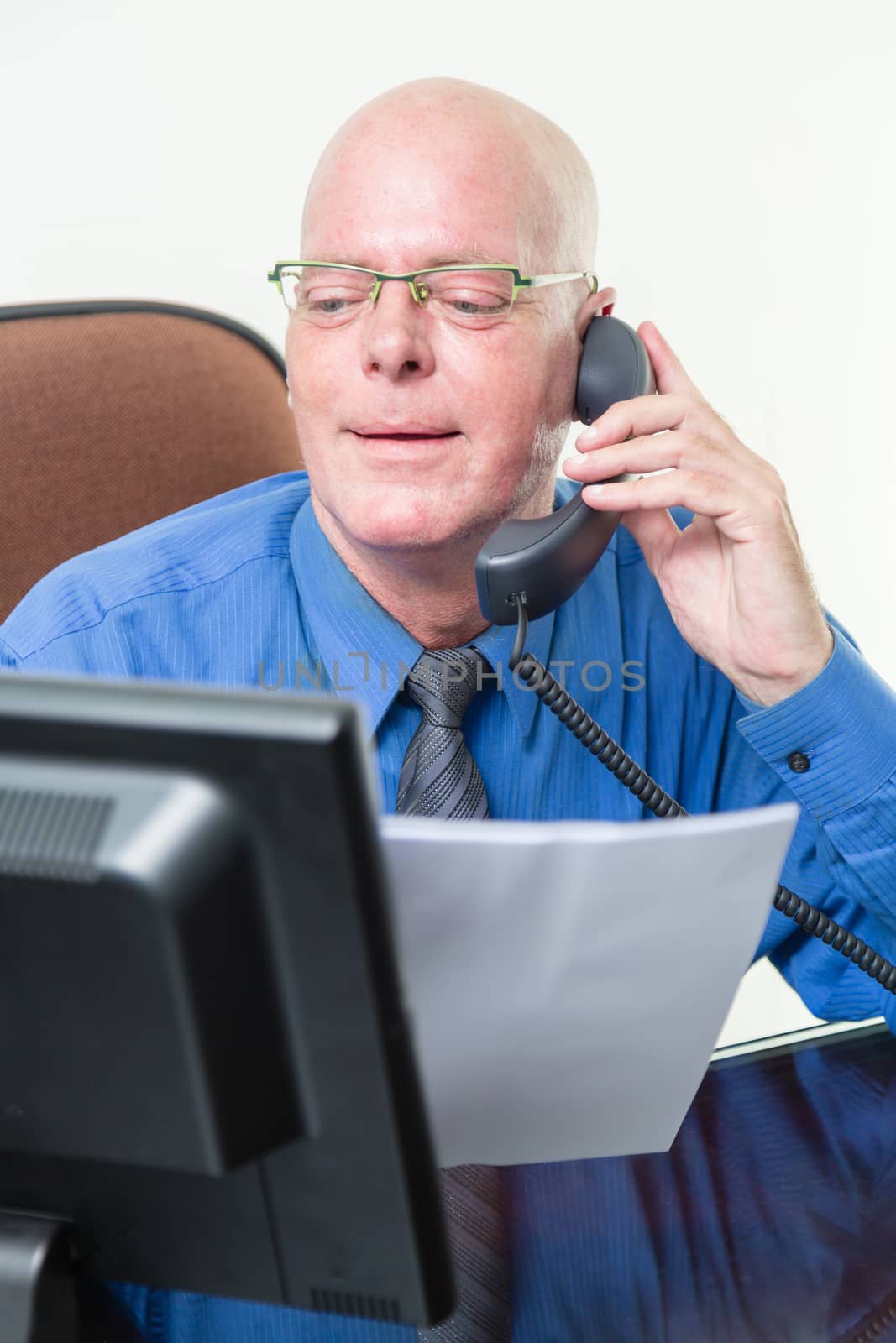 Corporate worker at desk comparing written notes with computer data