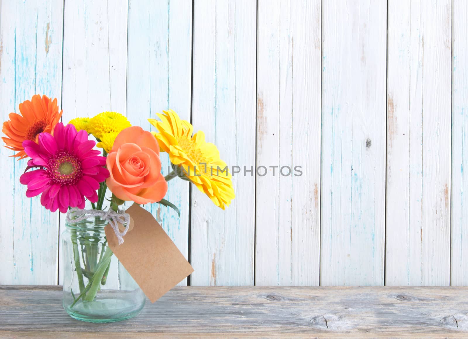 Mixed variety of flowers in a glass jar over a white background