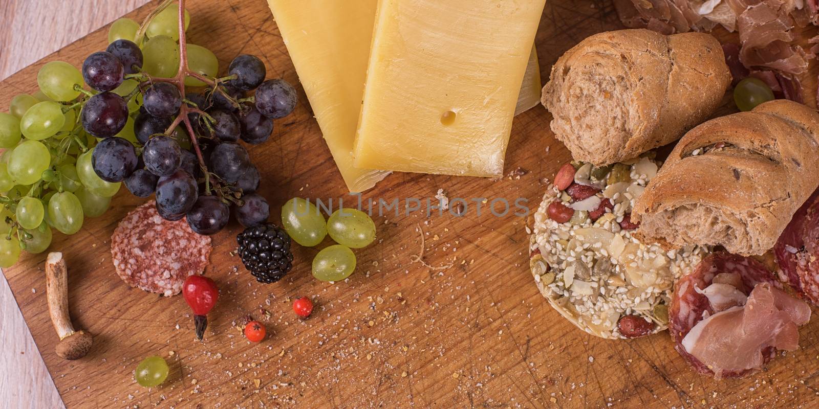 Fresh grapes, cheese bacon berries and salami on wooden table