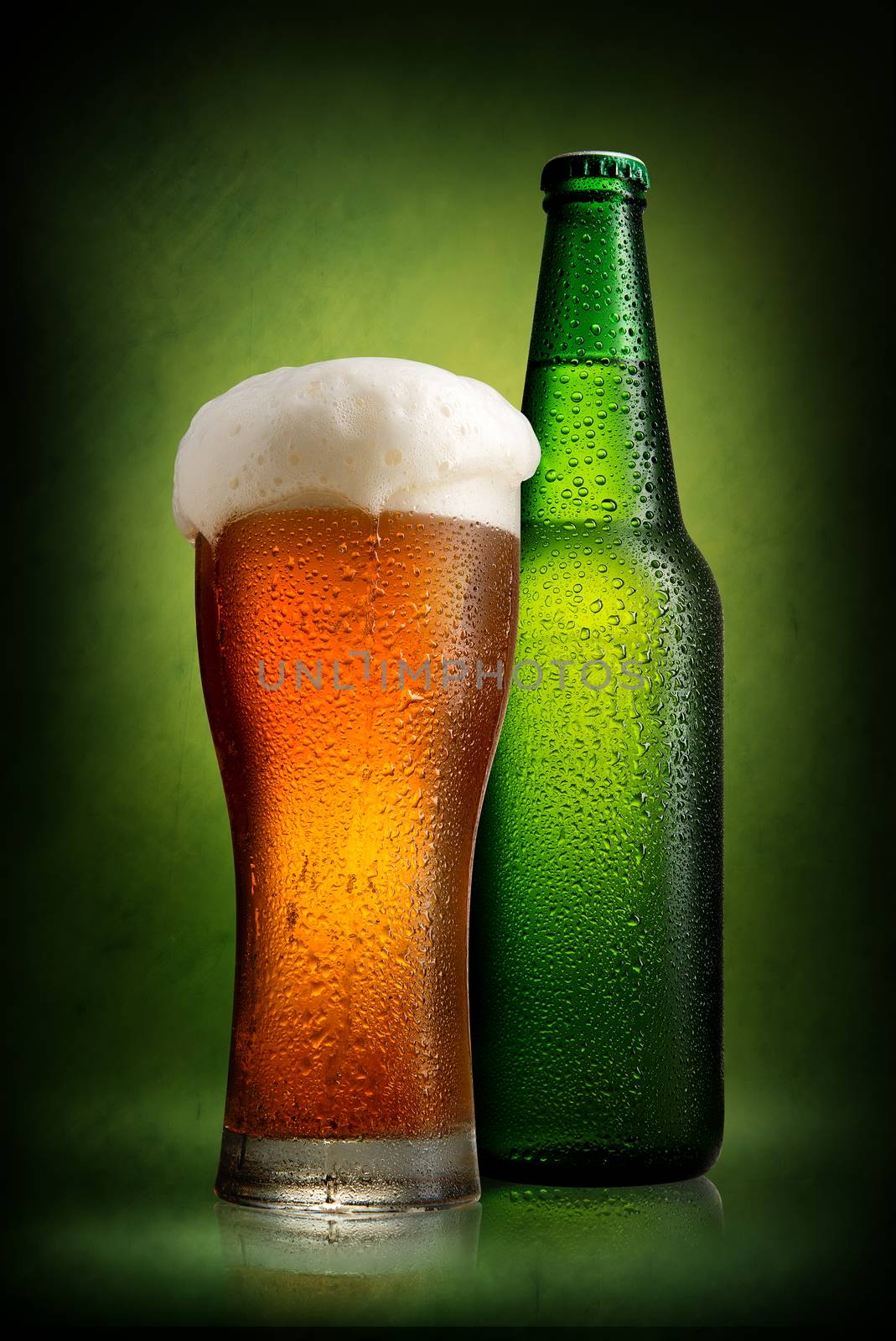 Beer in bottle and tall glass on a green background