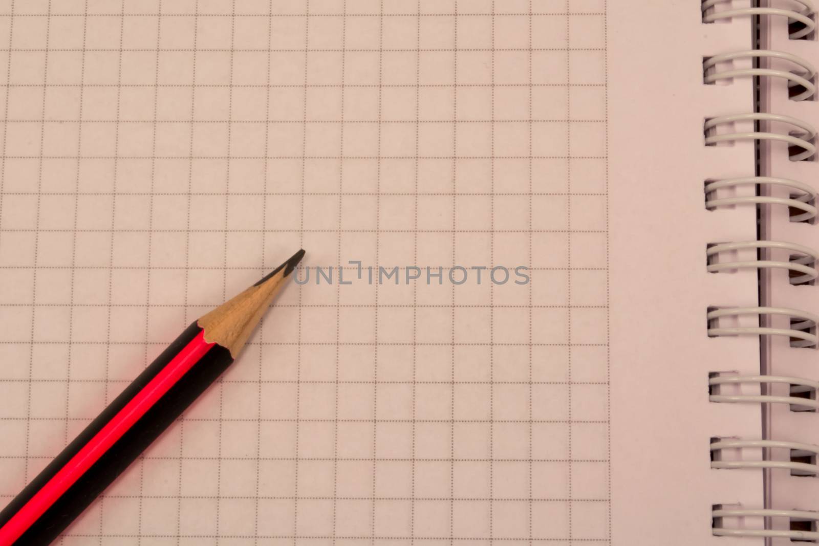 White empty notebook with pencil on top of it.