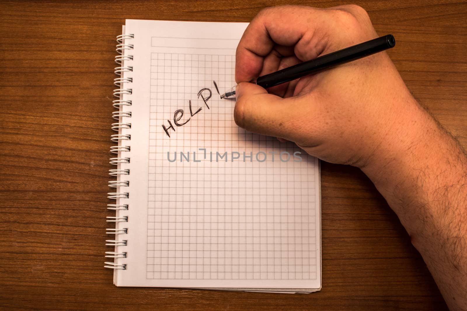 Hand with pencil and notebook. Help is written on the paper