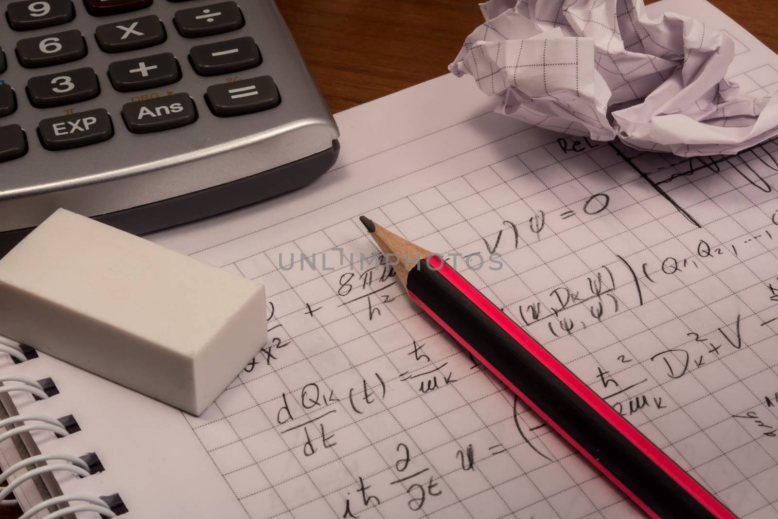 Messy table with notebook, pencils, crumpled papers and calculator
