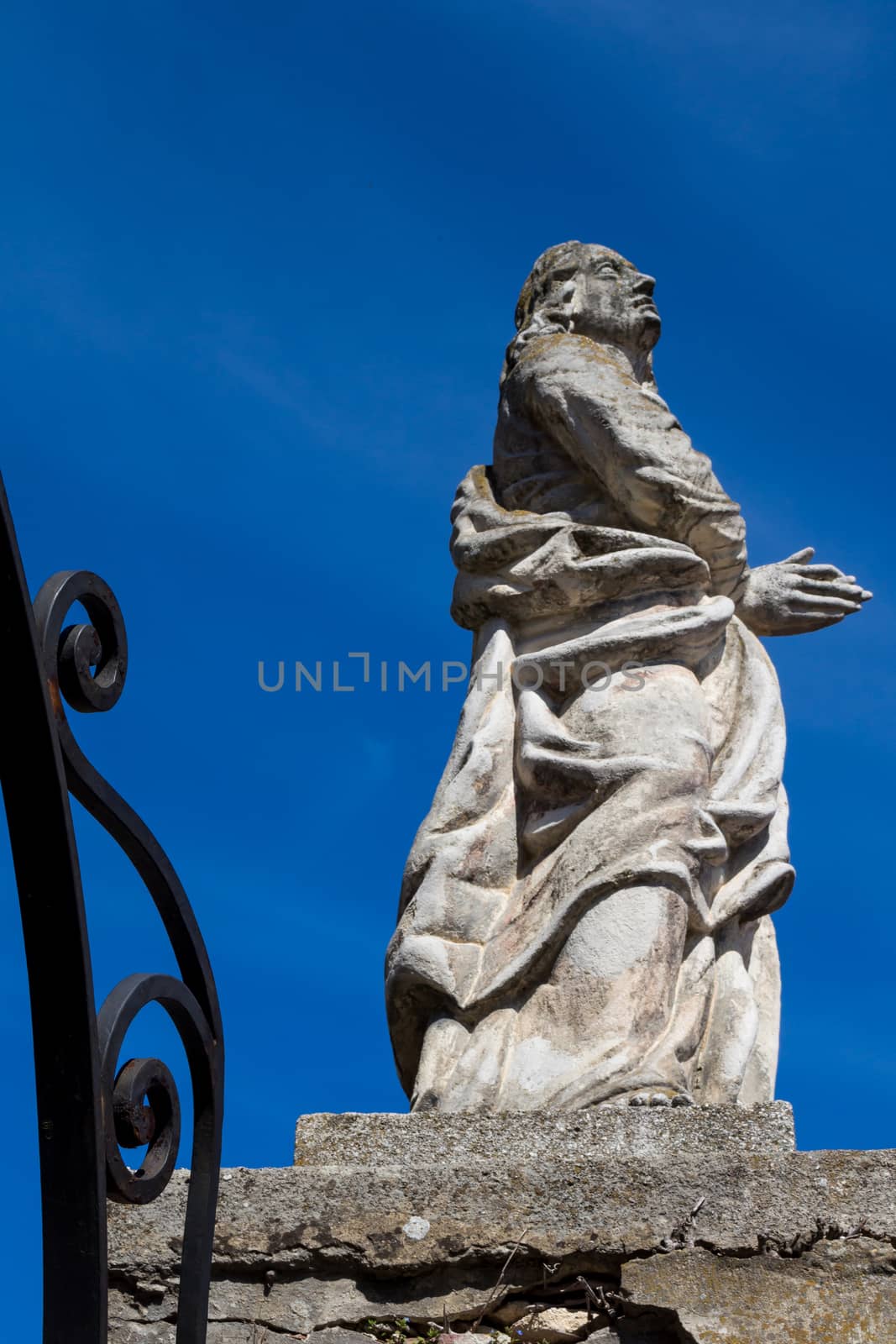 Entrance to the church of Saint George in Svaty Jur, Slovakia. Stone statue beside the gate. Intense blue sky.