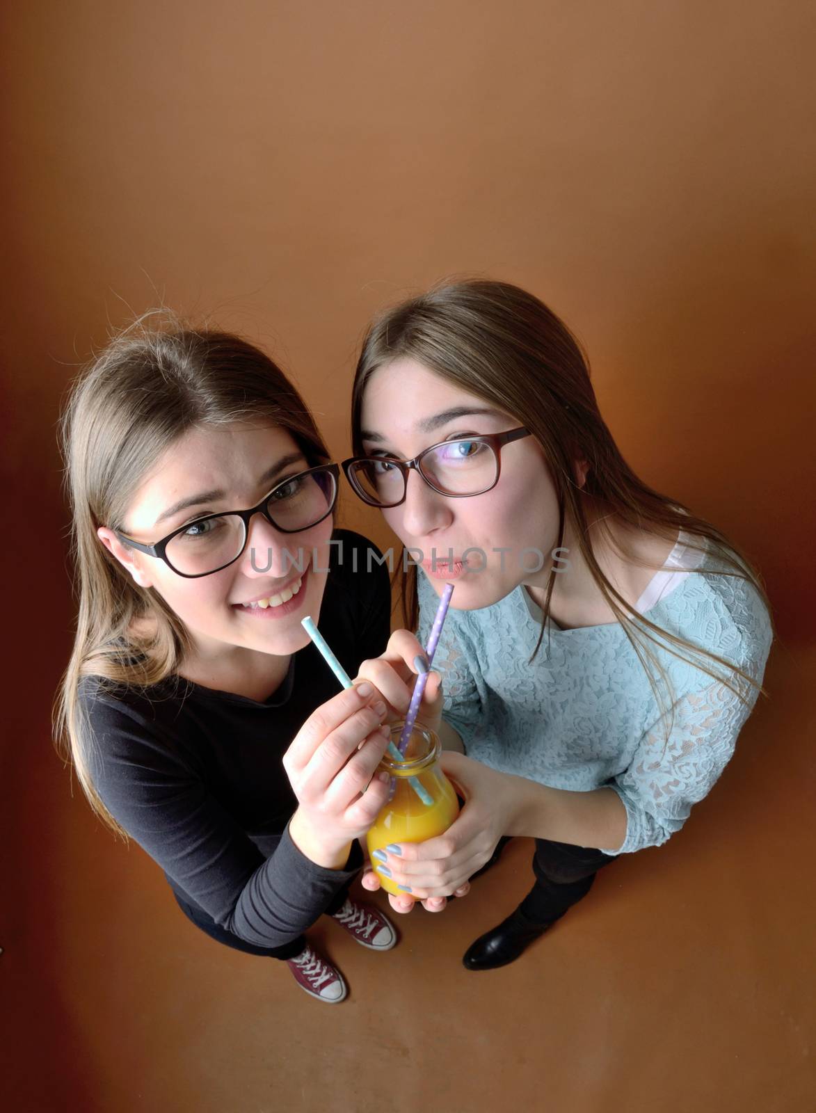 Teen girls drinking together orange juice