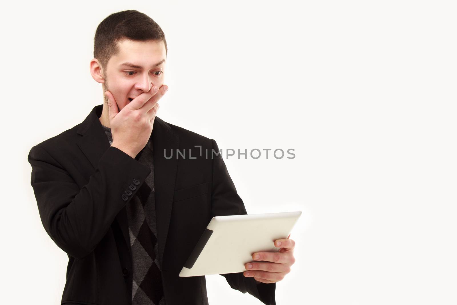 Casual businessman surprisedly looking  at his tablet screen isolated on white