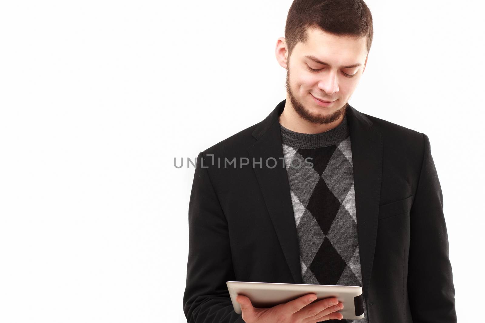 Casual businessman joyfully  looking  at his tablet screen  isolated on white