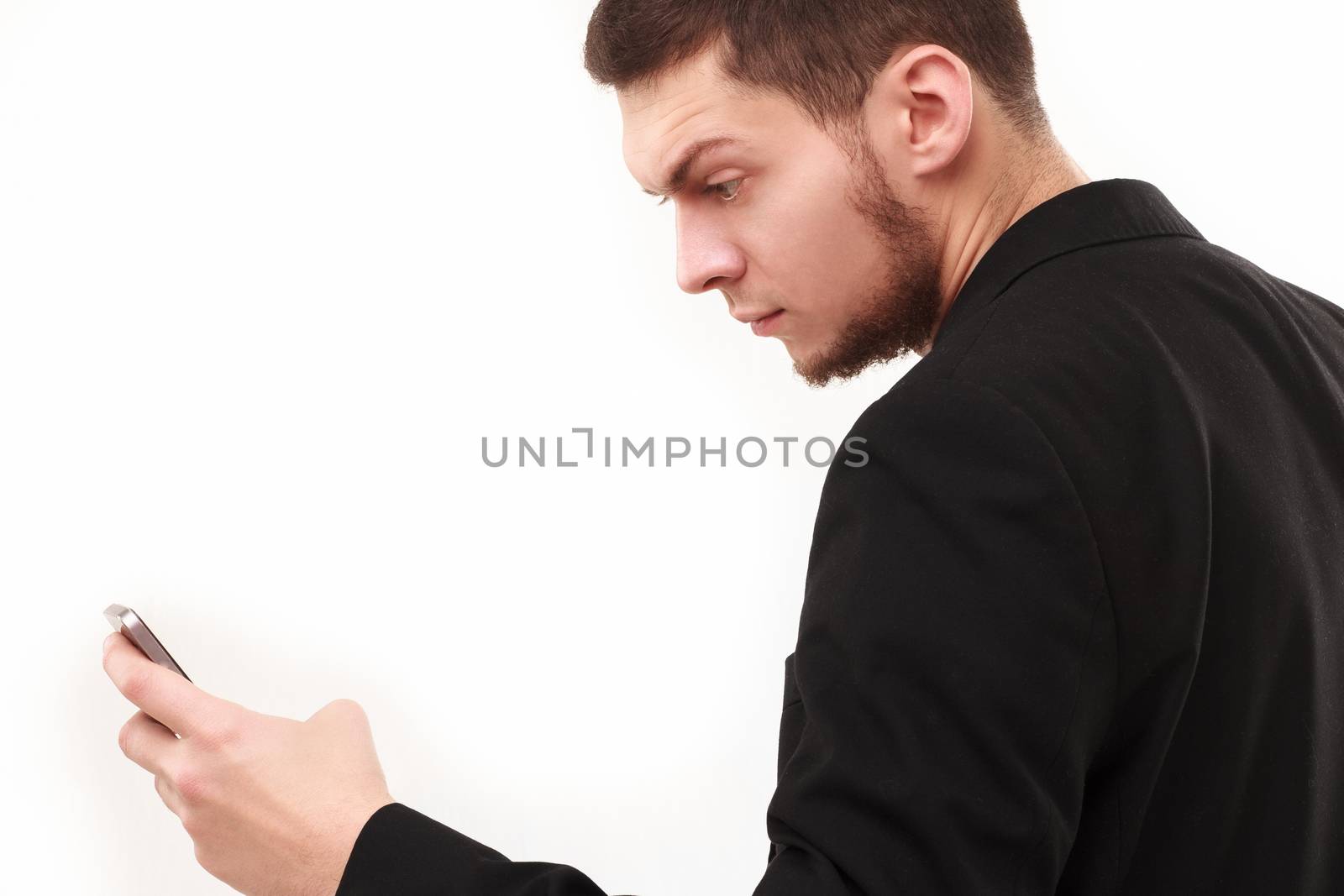 Businessman with a raised eyebrow using his phone isolated on white
