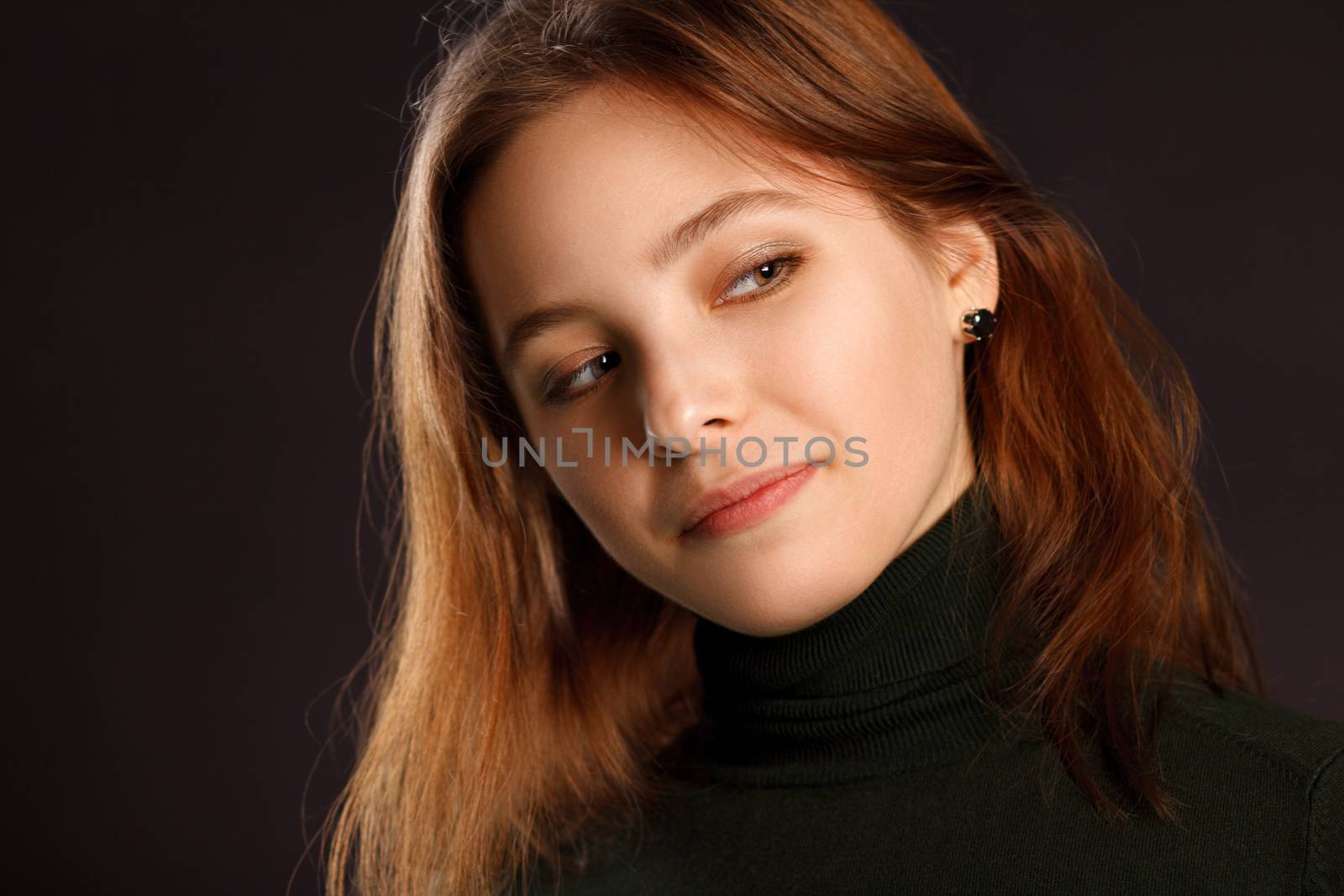 Closeup headshot portrait of redhead woman on dark background