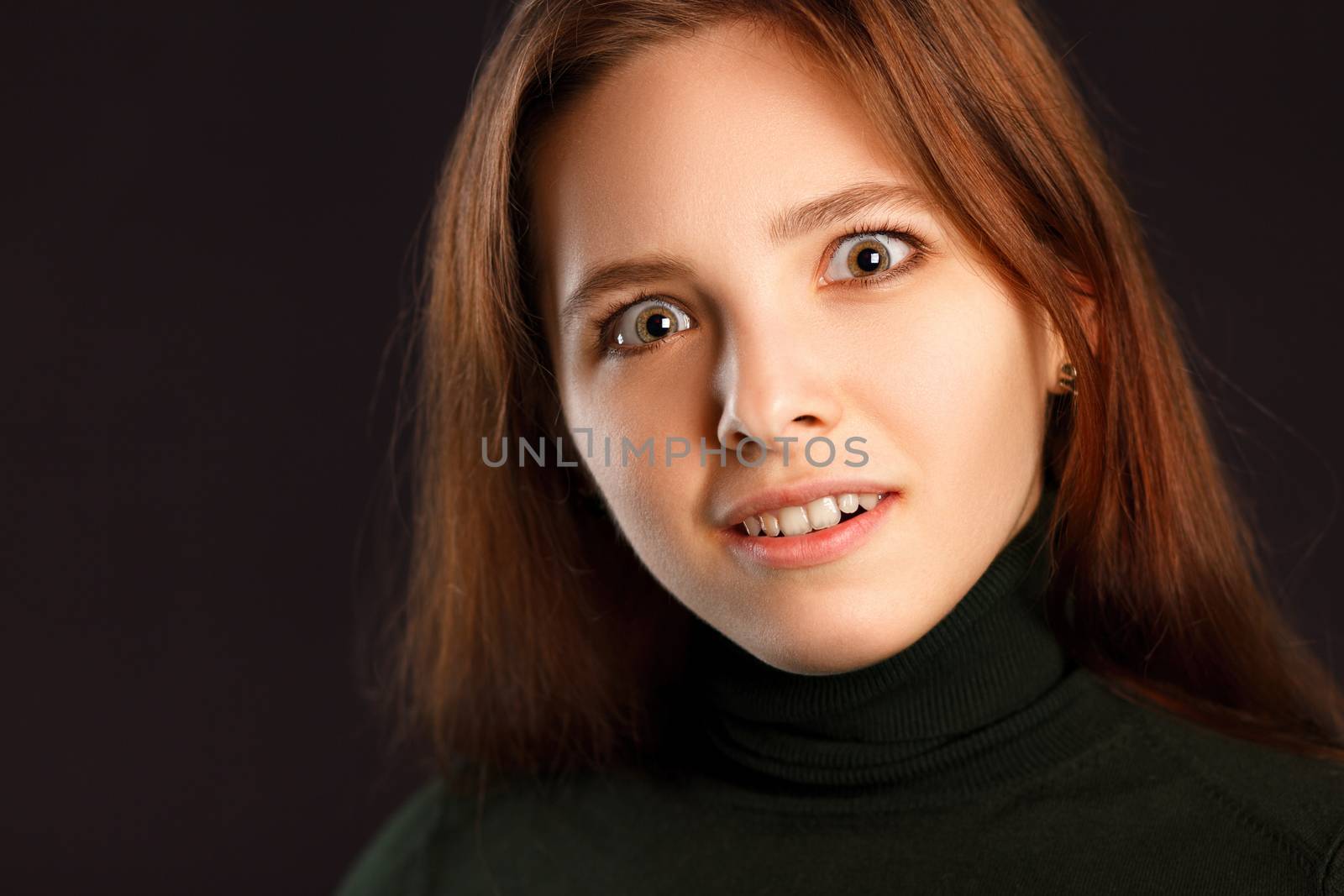 Portrait of surprised redhead woman on dark background