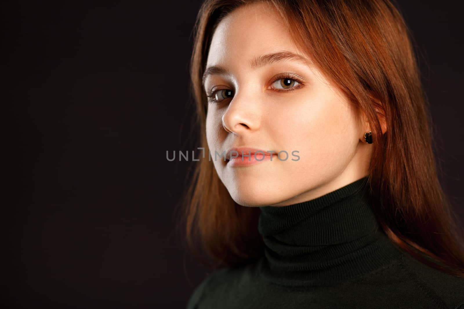 Closeup headshot portrait of redhead woman on dark background