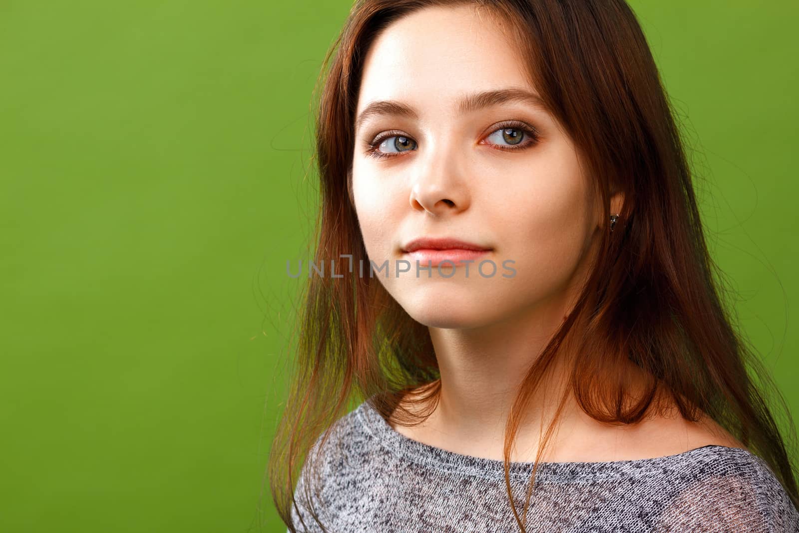 Portrait of young smiling girl looking right on green