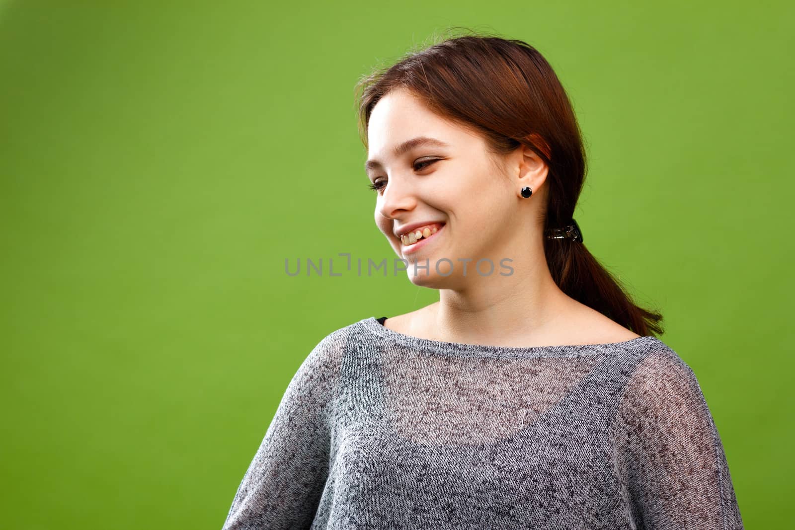 Portrait of young laughing girl looking left on green
