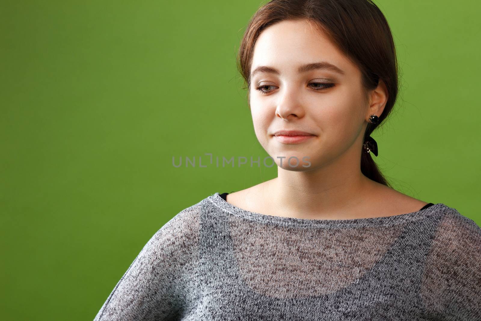 Portrait of teenage girl looking down on green background