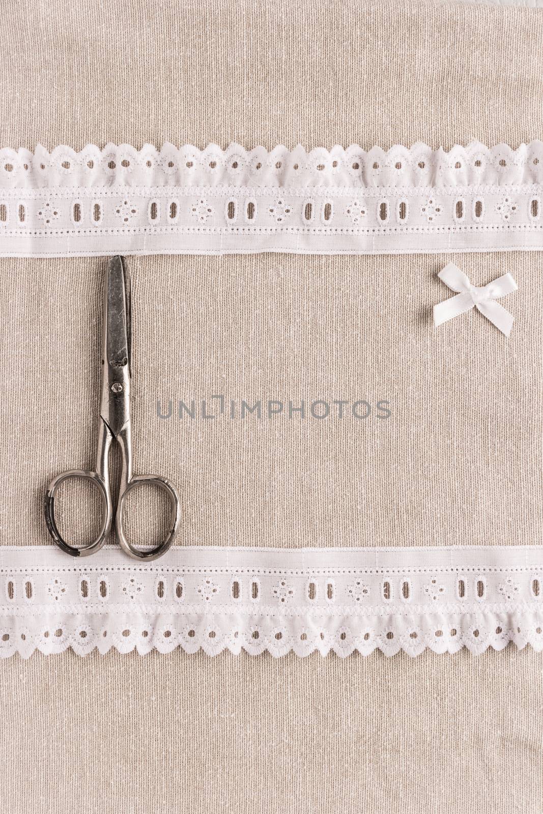 Rustic fabric for sewing, lace, scissors and accessories for needlework on old wooden background. Top view with copy space.