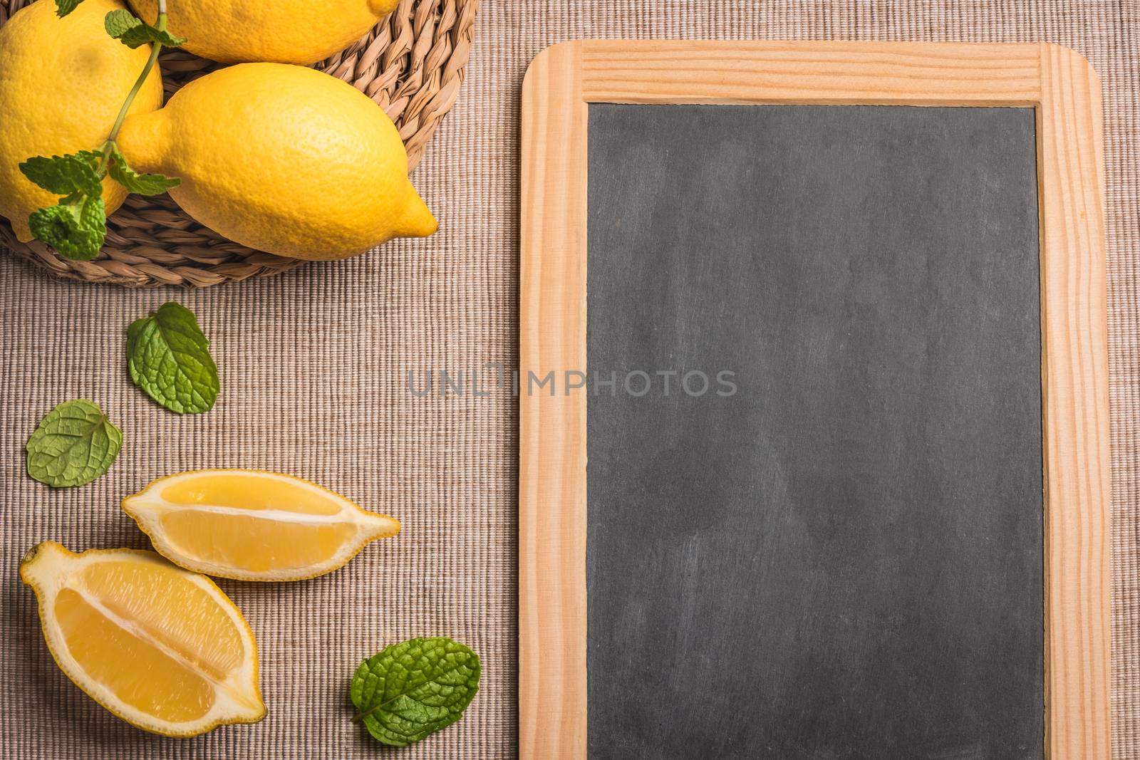 Slices and half fresh juicy lemon with mint leaves and slate board. Top view with copy space.