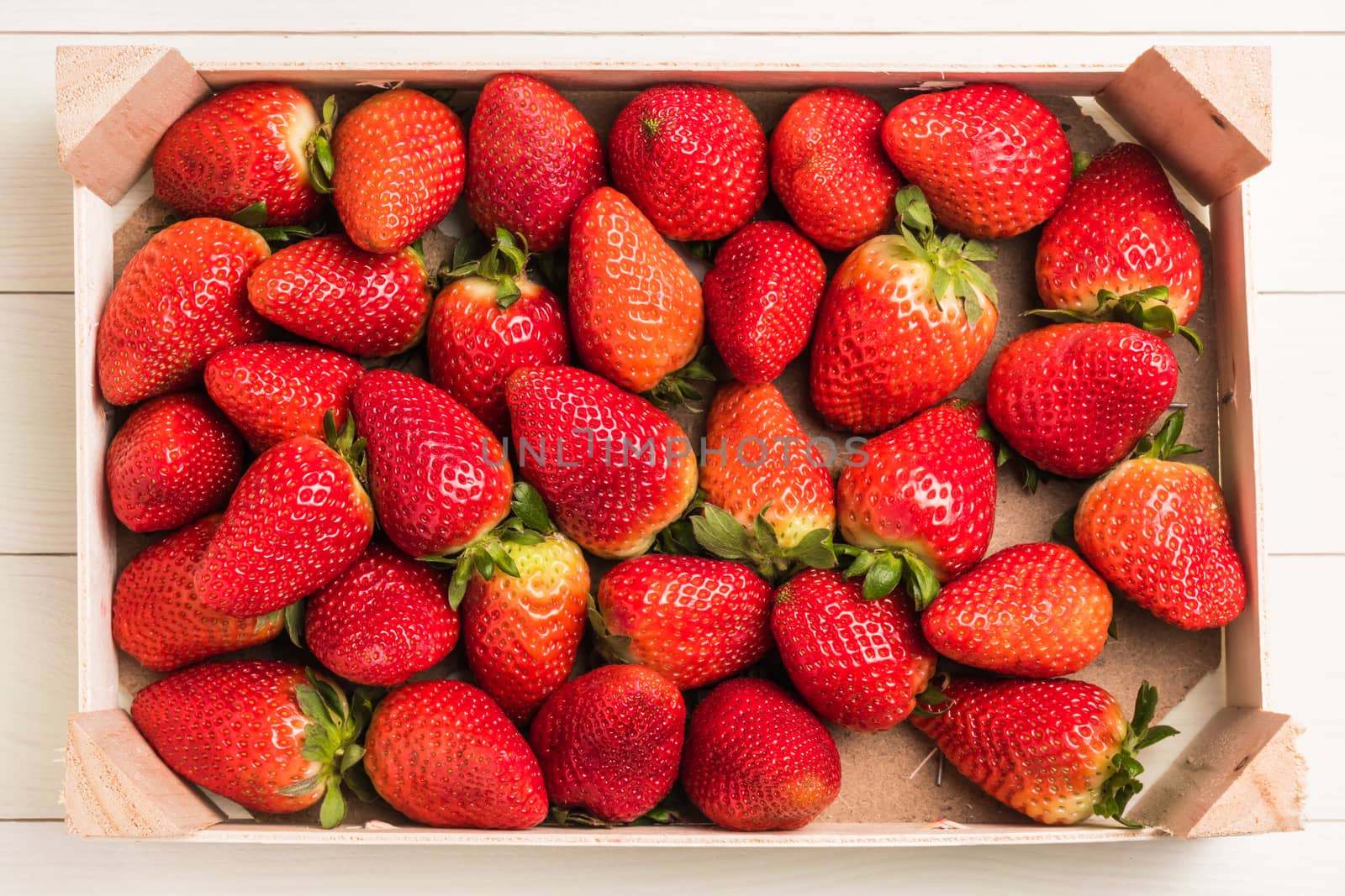 Fresh strawberries in wooden basket on wooden table. Top view with copy space