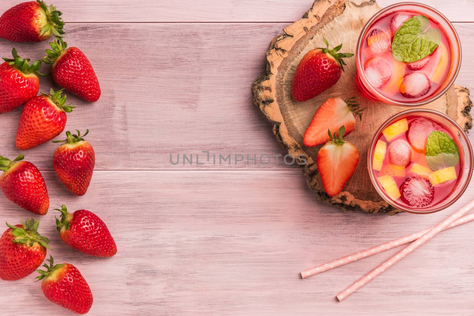 Refreshing summer drink with strawberry, lemon and ice in glasses on the vintage wooden table. Top view with copy space.